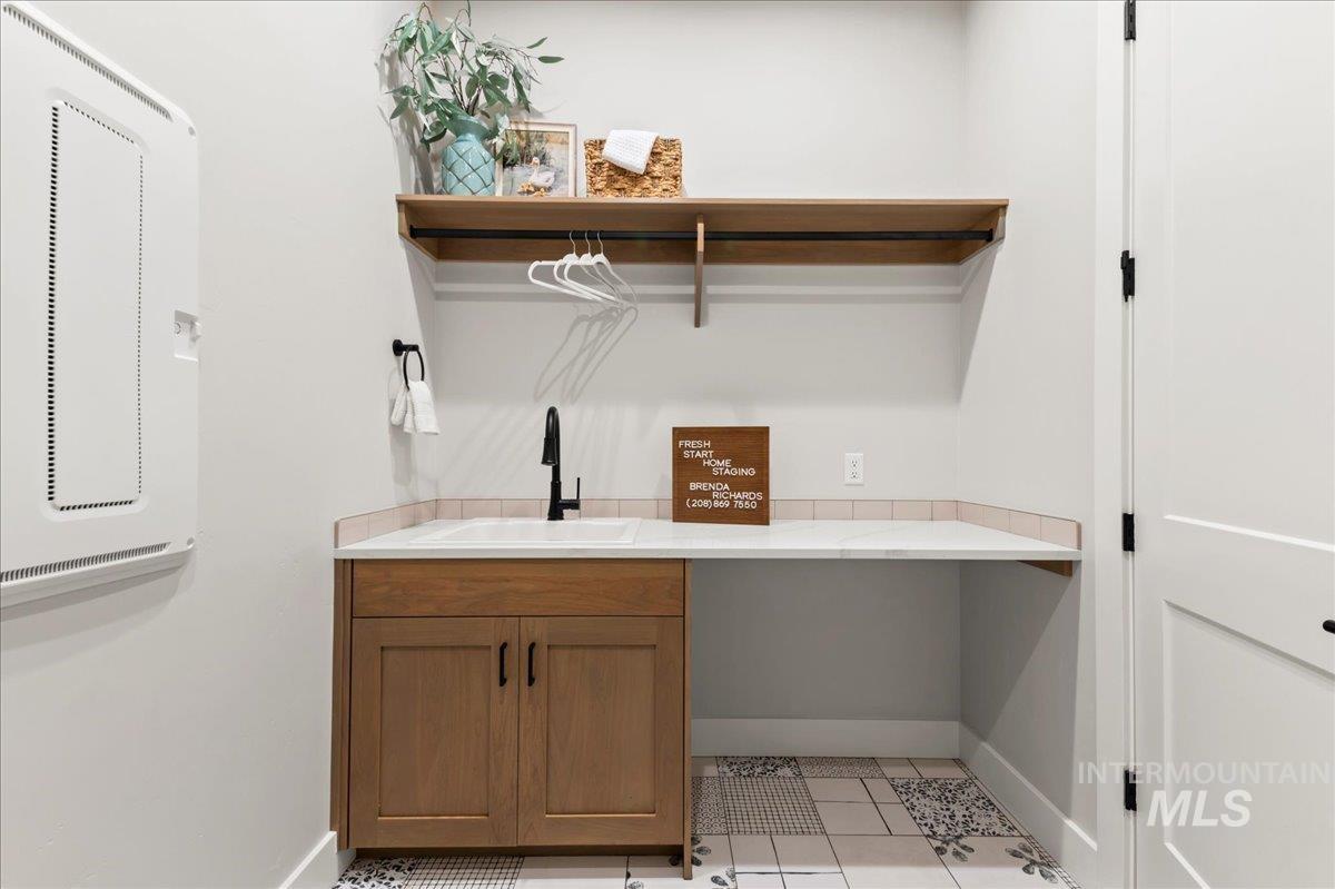 Laundry area featuring light tile patterned floors and a sink