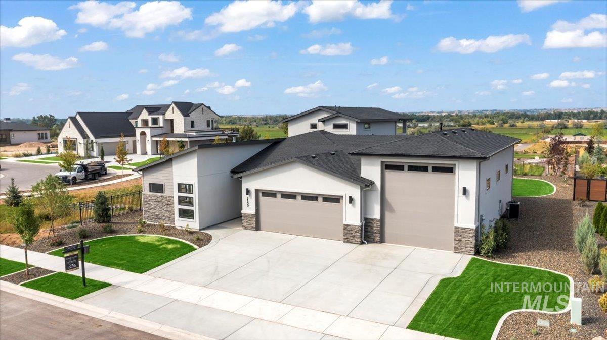 View of front of property featuring a garage, concrete driveway, stucco siding, and stone siding