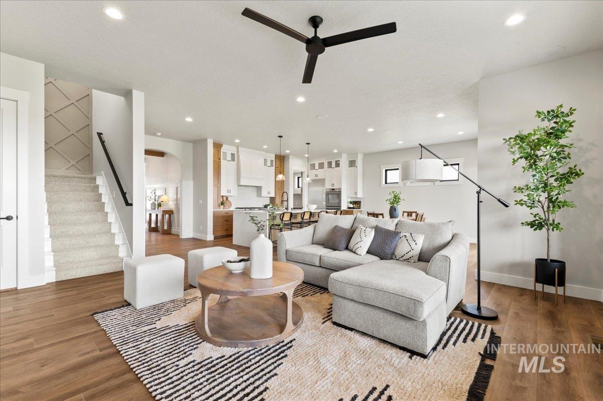 Living room with stairway, recessed lighting, arched walkways, wood finished floors, and ceiling fan