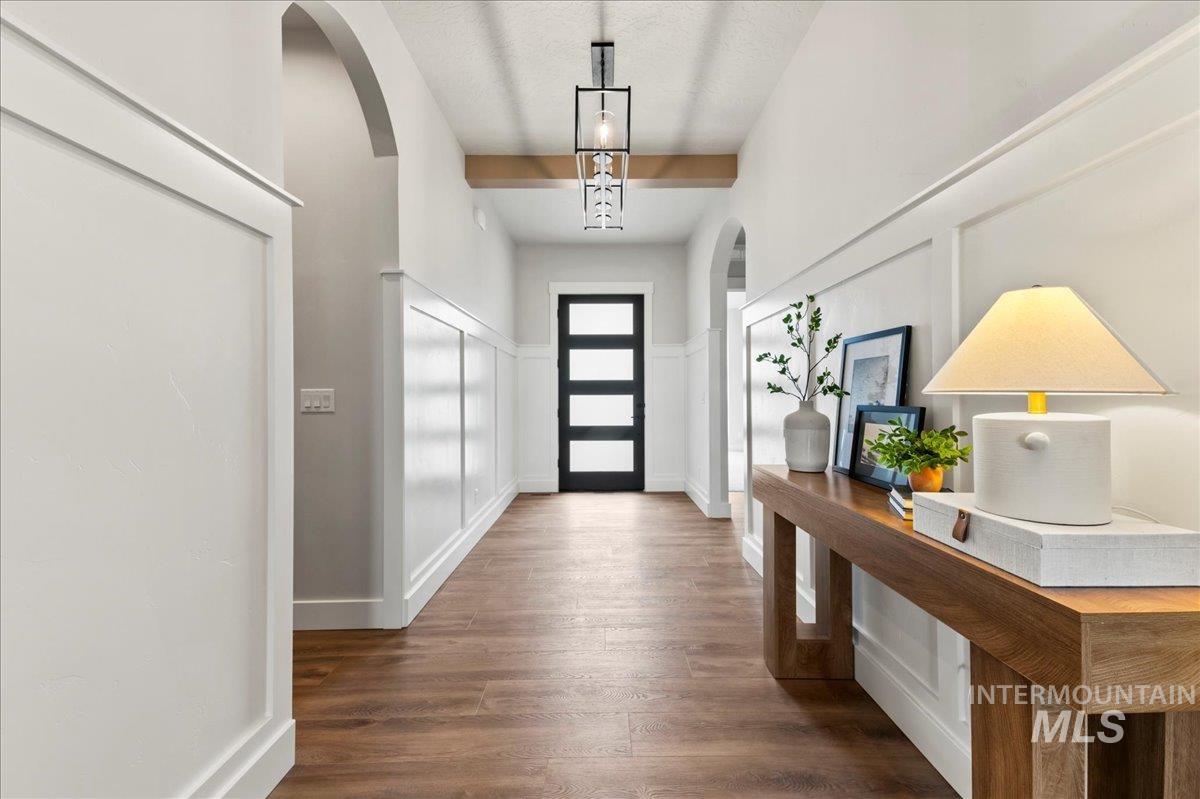 Doorway with arched walkways, wood finished floors, and a decorative wall