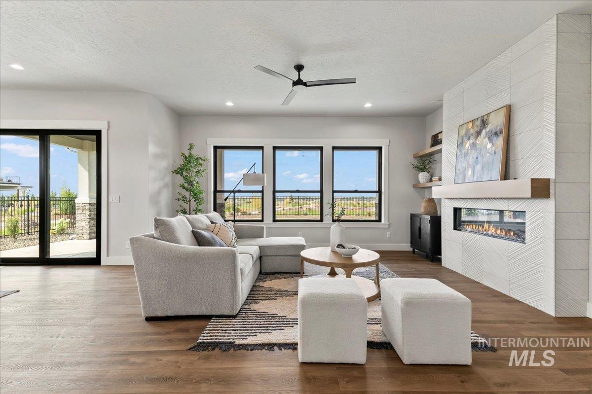 Living area featuring wood finished floors, ceiling fan, a fireplace, a textured ceiling, and recessed lighting