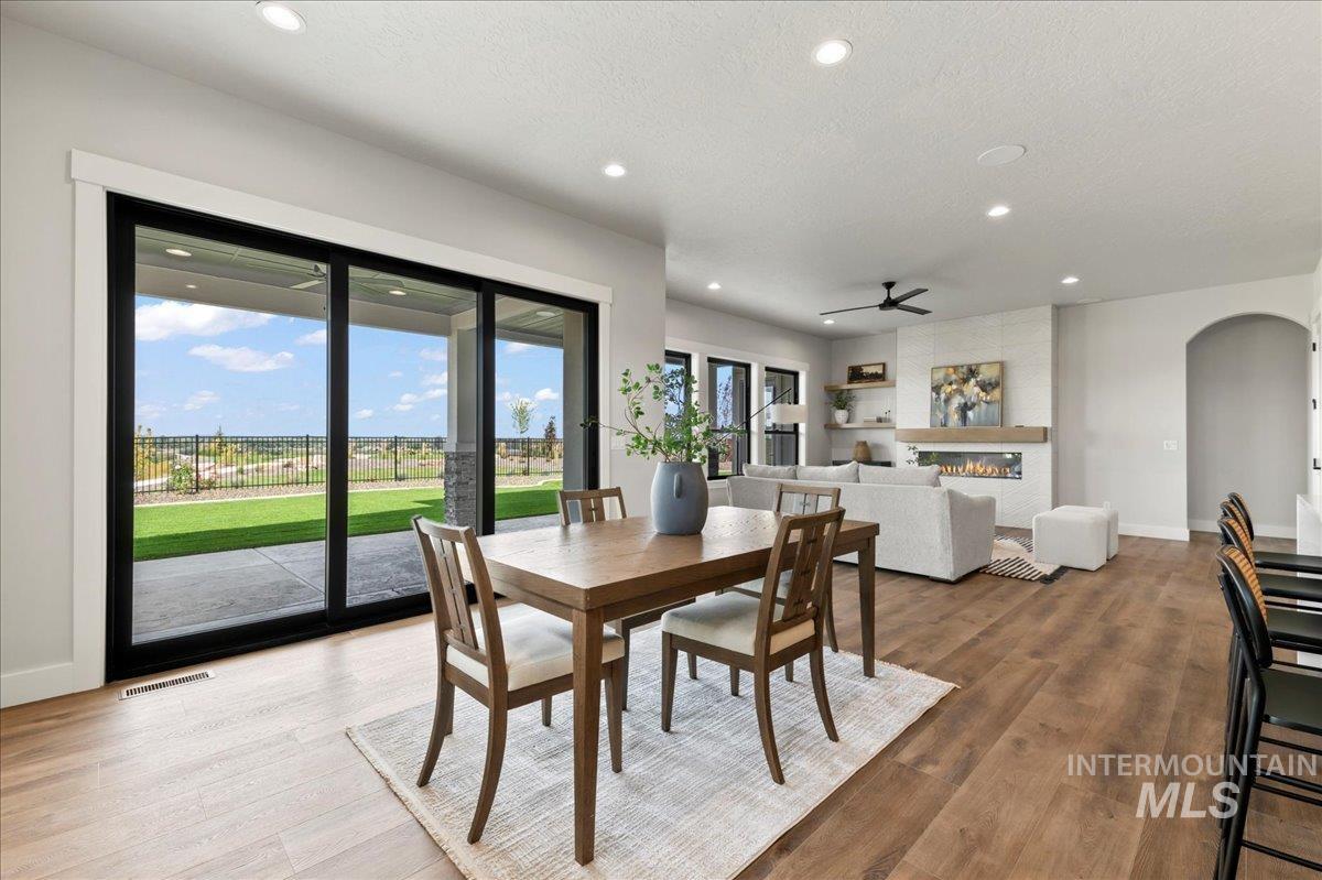 Dining space with a fireplace, recessed lighting, arched walkways, light wood-style flooring, and a textured ceiling