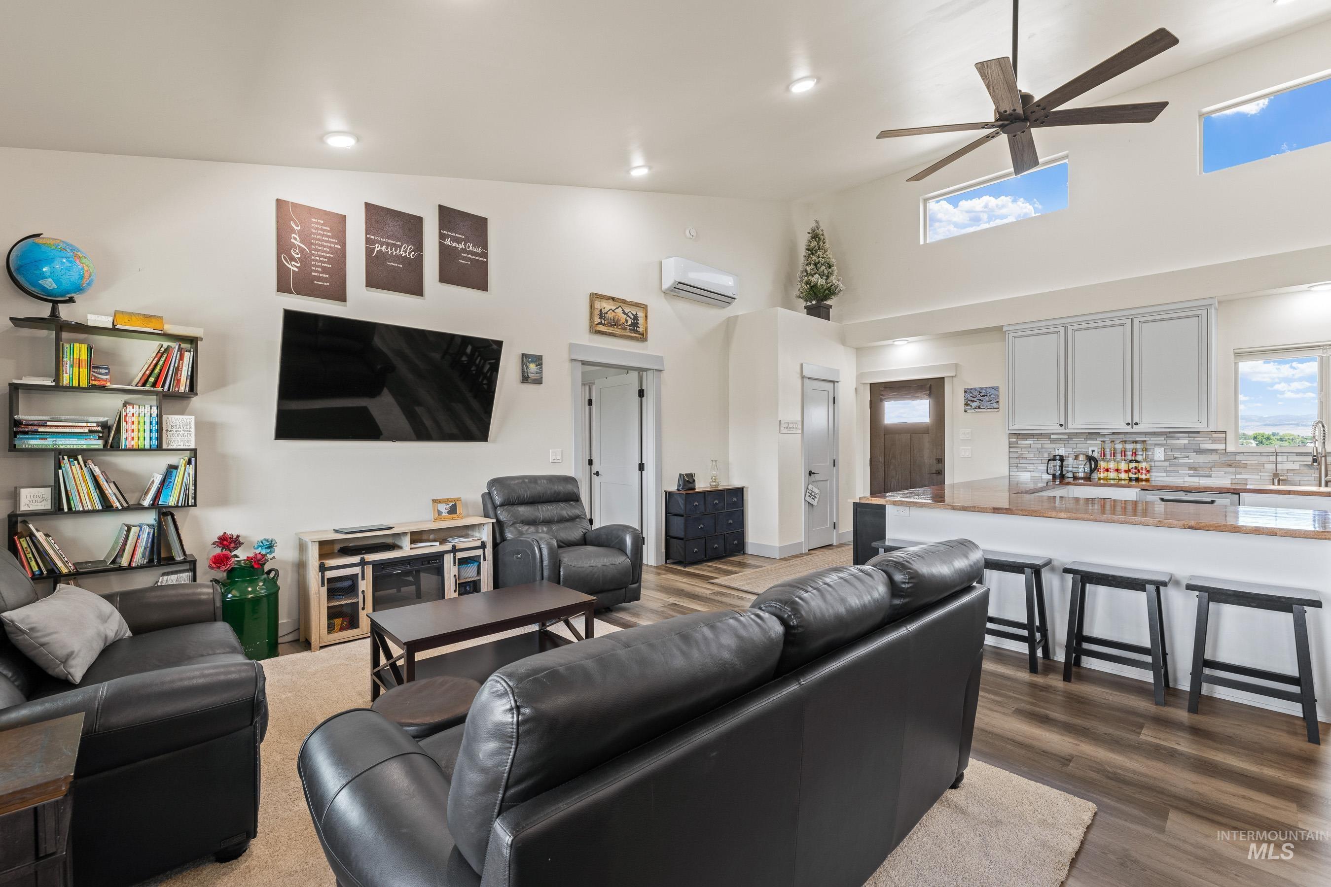 Living area featuring ceiling fan, dark wood-style flooring, high vaulted ceiling, a wall mounted AC, and recessed lighting
