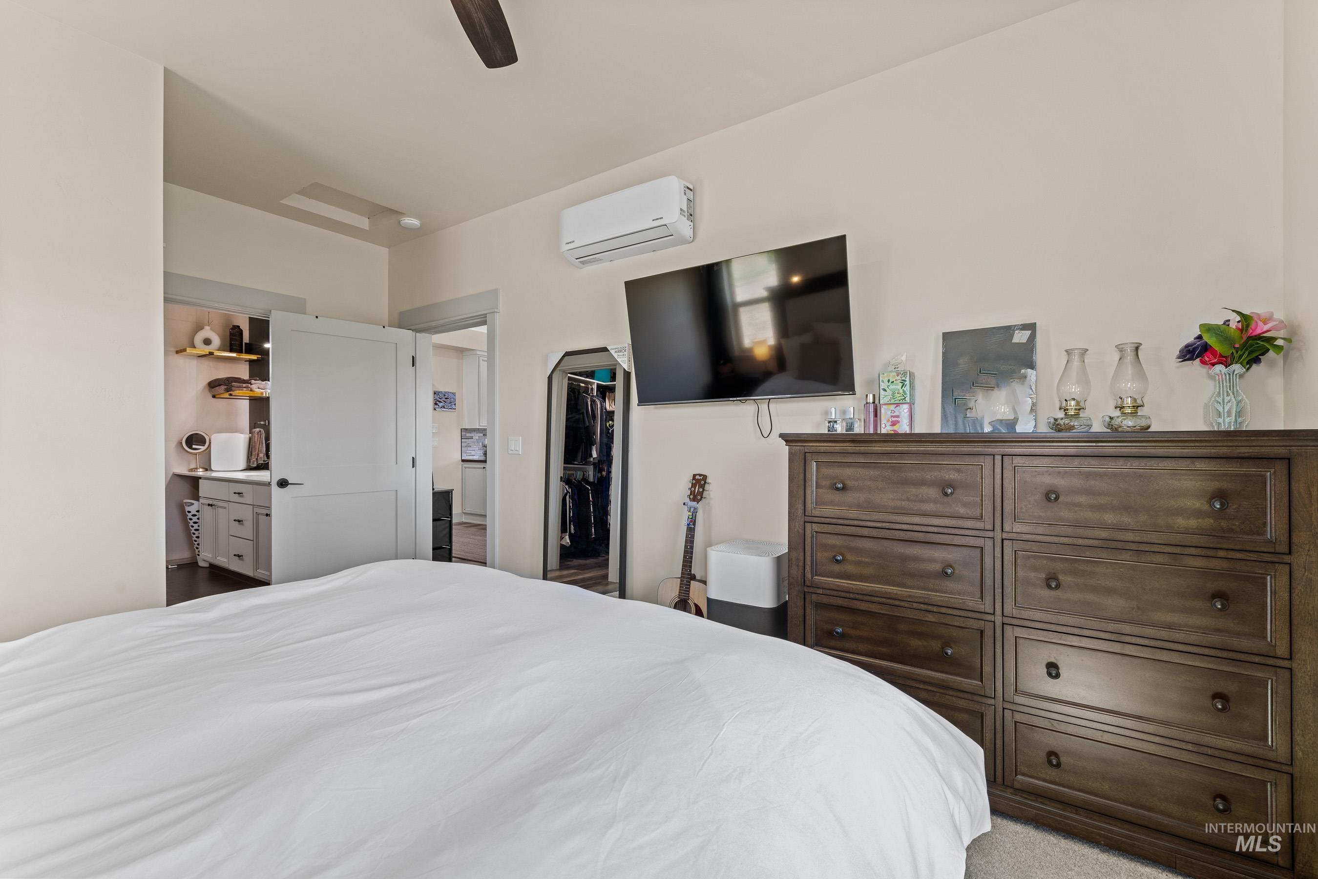 Bedroom featuring a wall mounted AC, a walk in closet, a ceiling fan, and a closet
