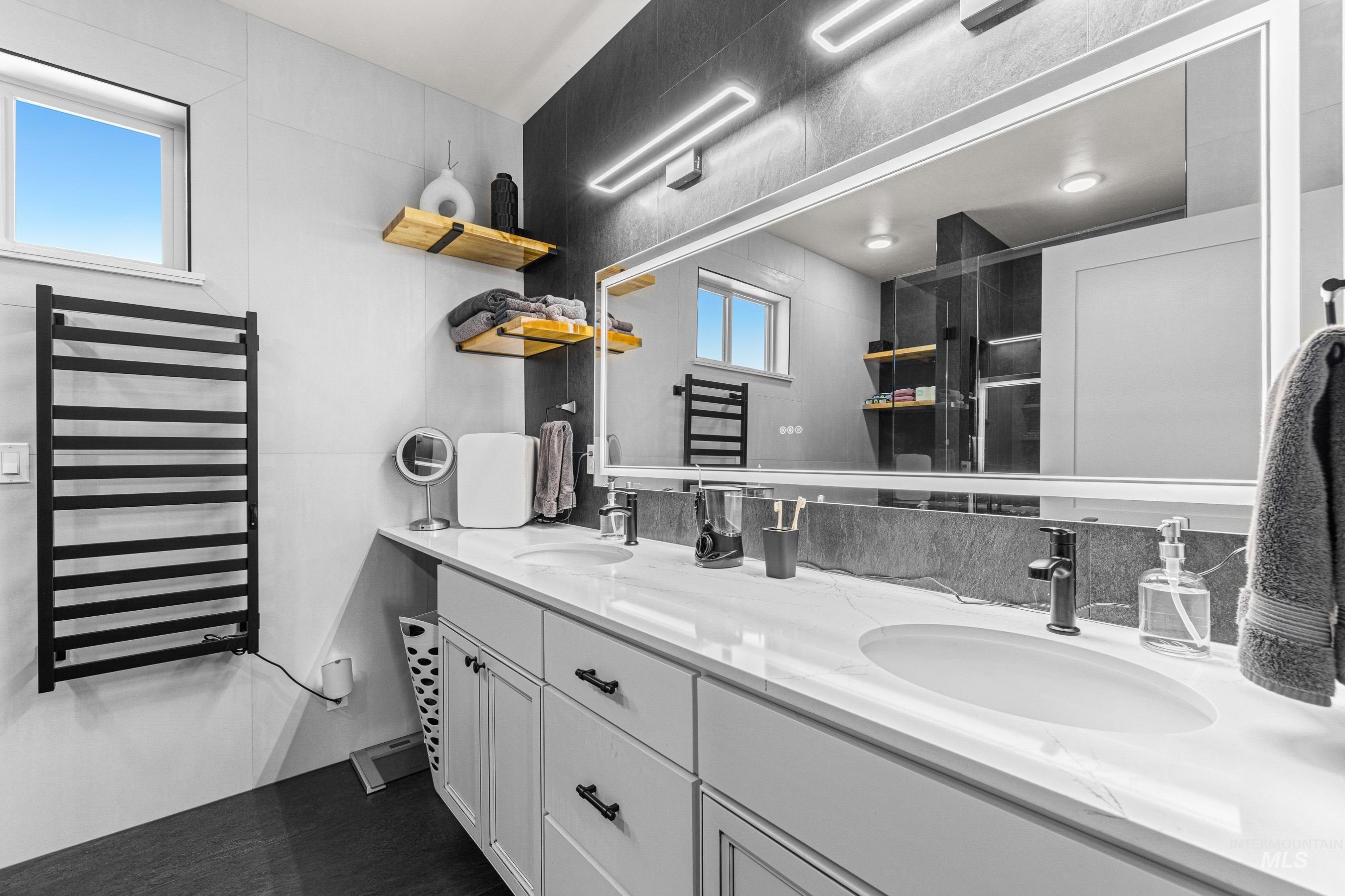 Full bath with radiator heating unit, a towel warmer, double vanity, and a shower