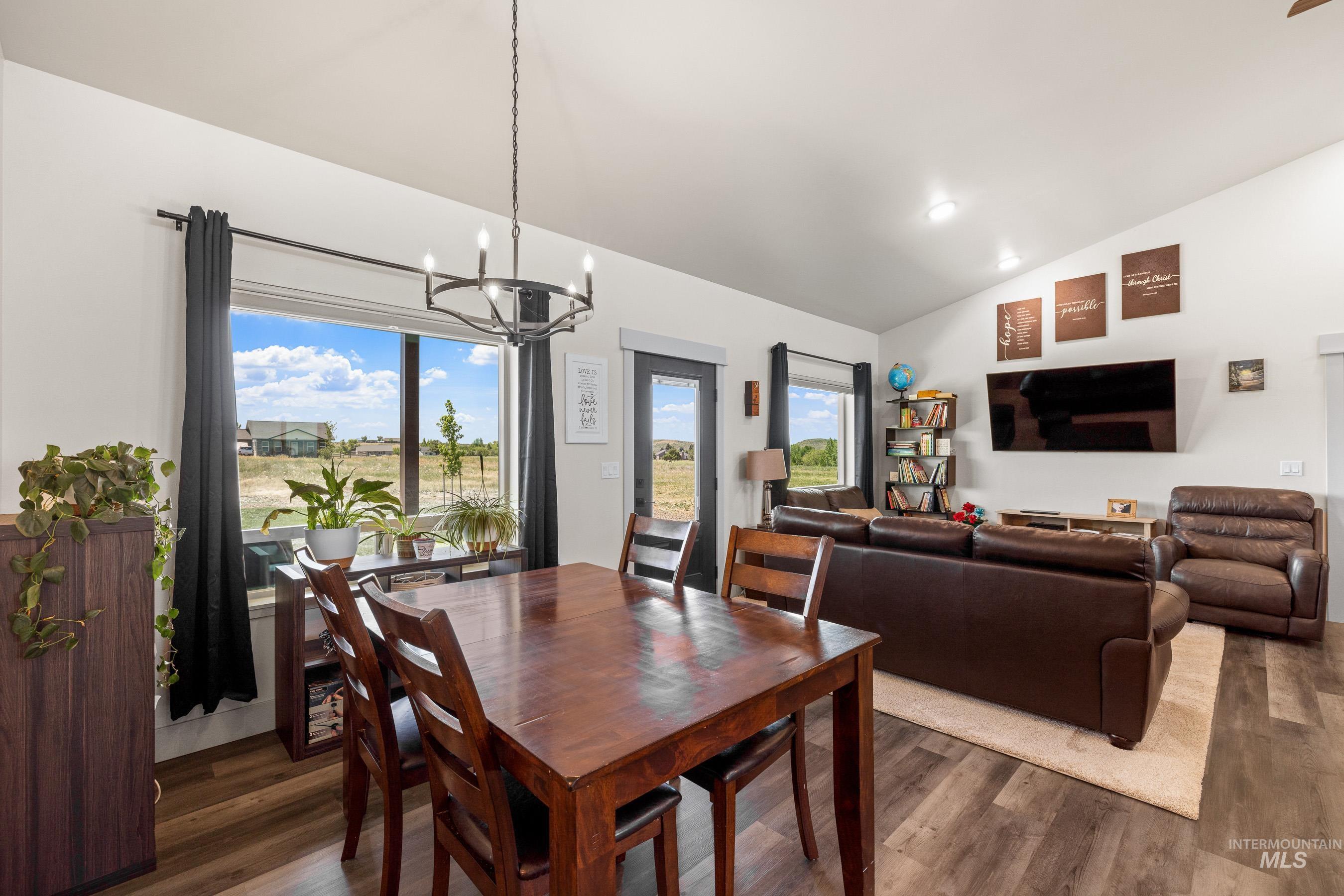 Dining room with a chandelier, lofted ceiling, wood finished floors, and recessed lighting