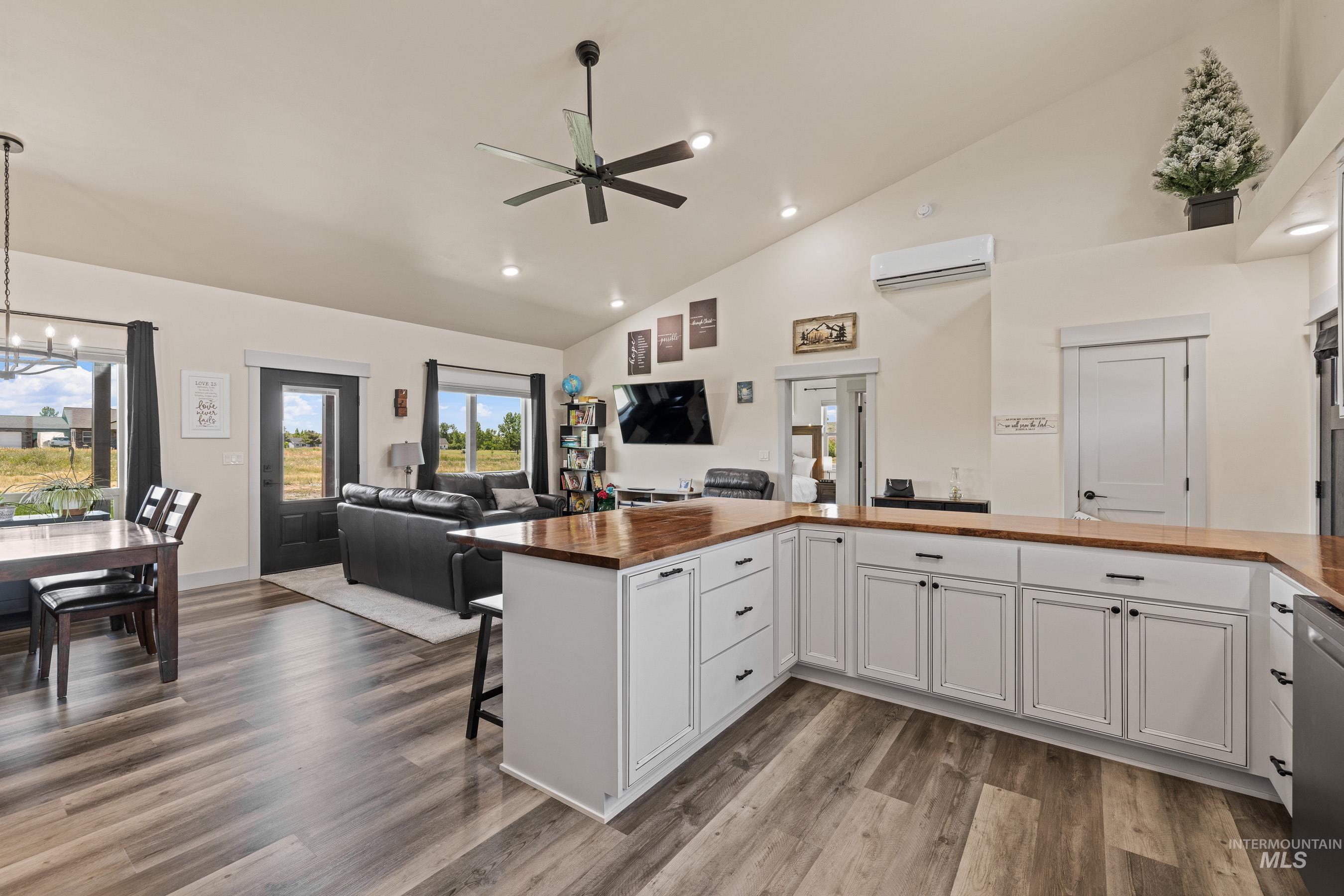 Kitchen featuring wooden counters, open floor plan, ceiling fan, a wall mounted air conditioner, and a chandelier