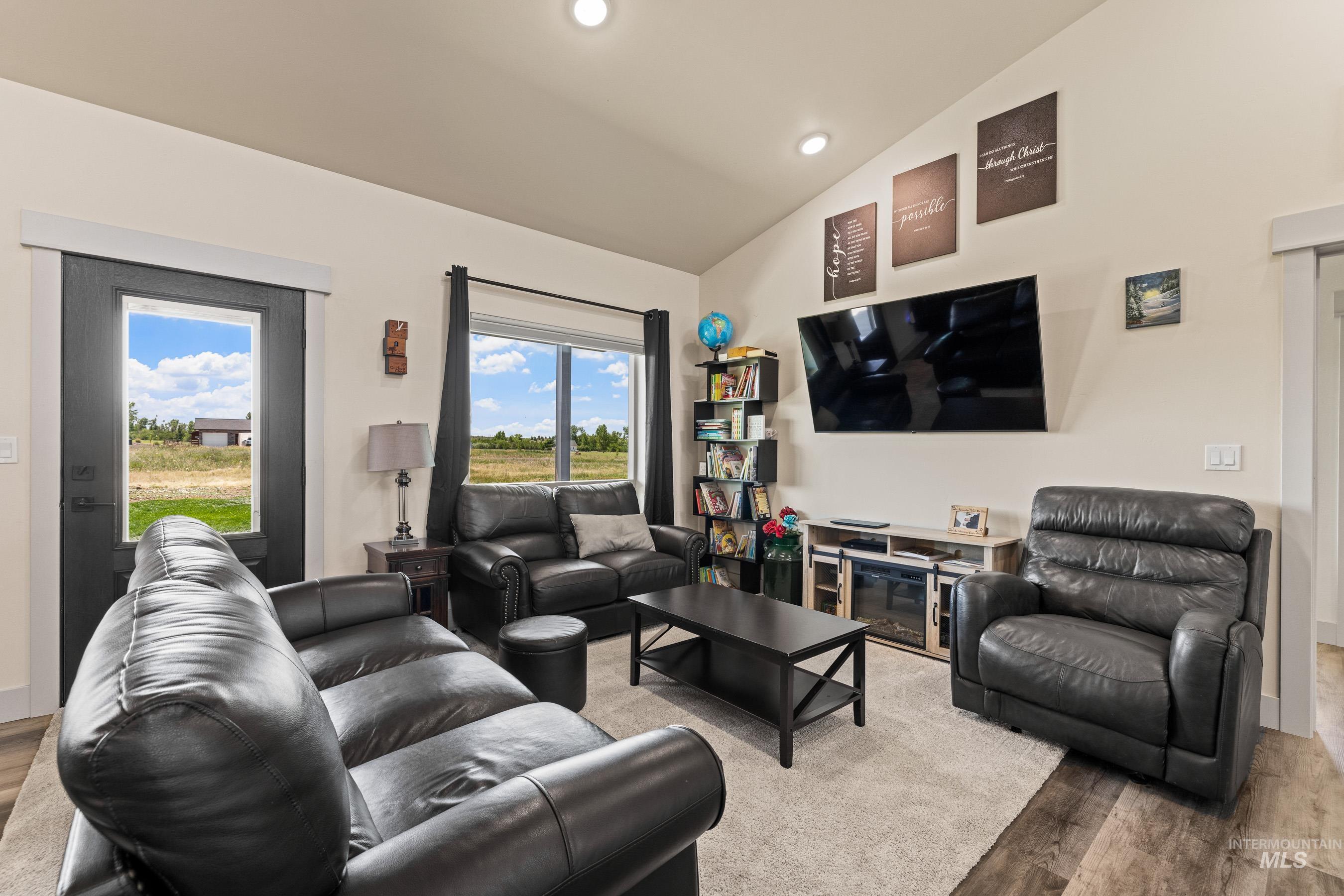 Living room with lofted ceiling, wood finished floors, healthy amount of natural light, and recessed lighting