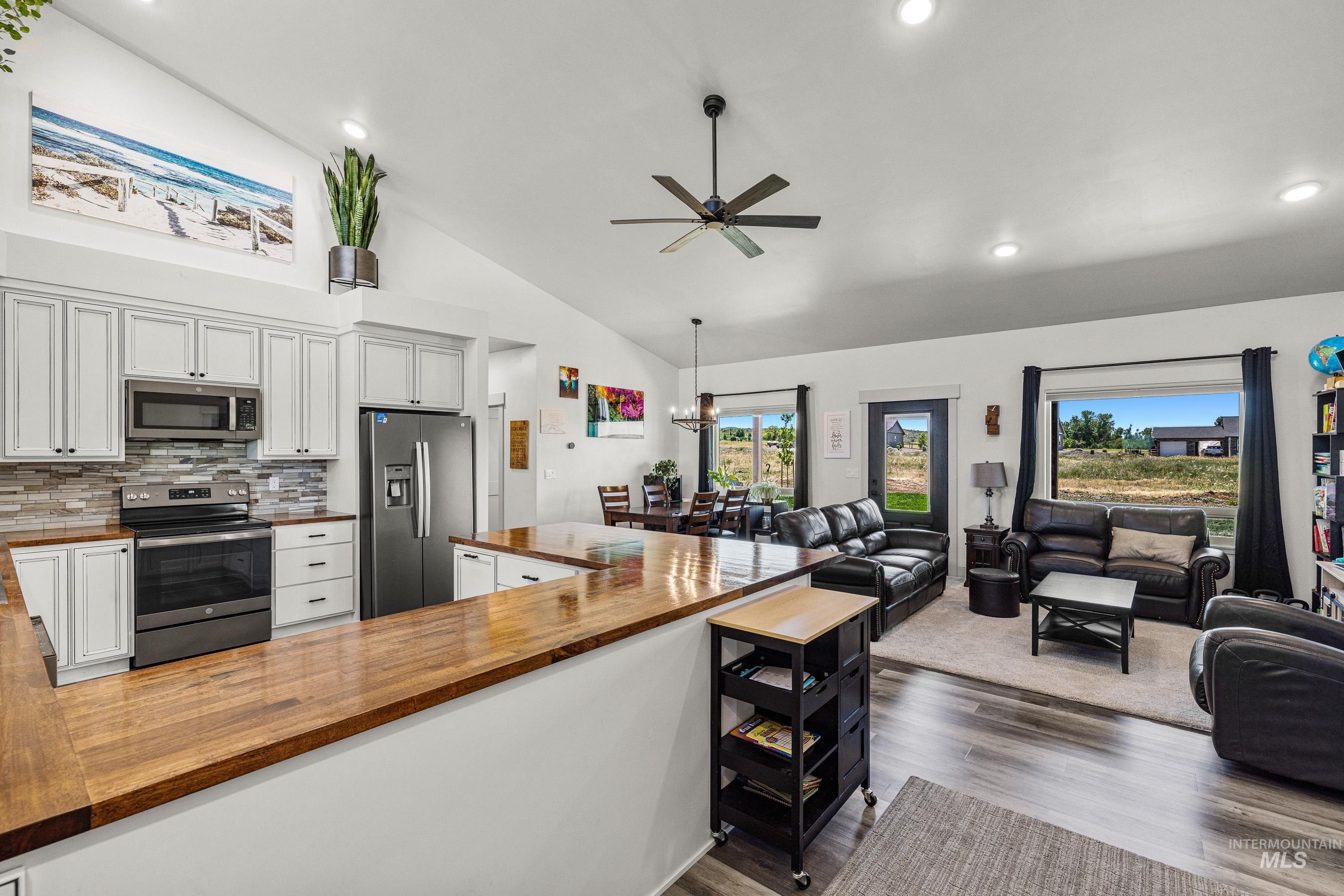 Kitchen featuring wood counters, appliances with stainless steel finishes, open floor plan, recessed lighting, and high vaulted ceiling