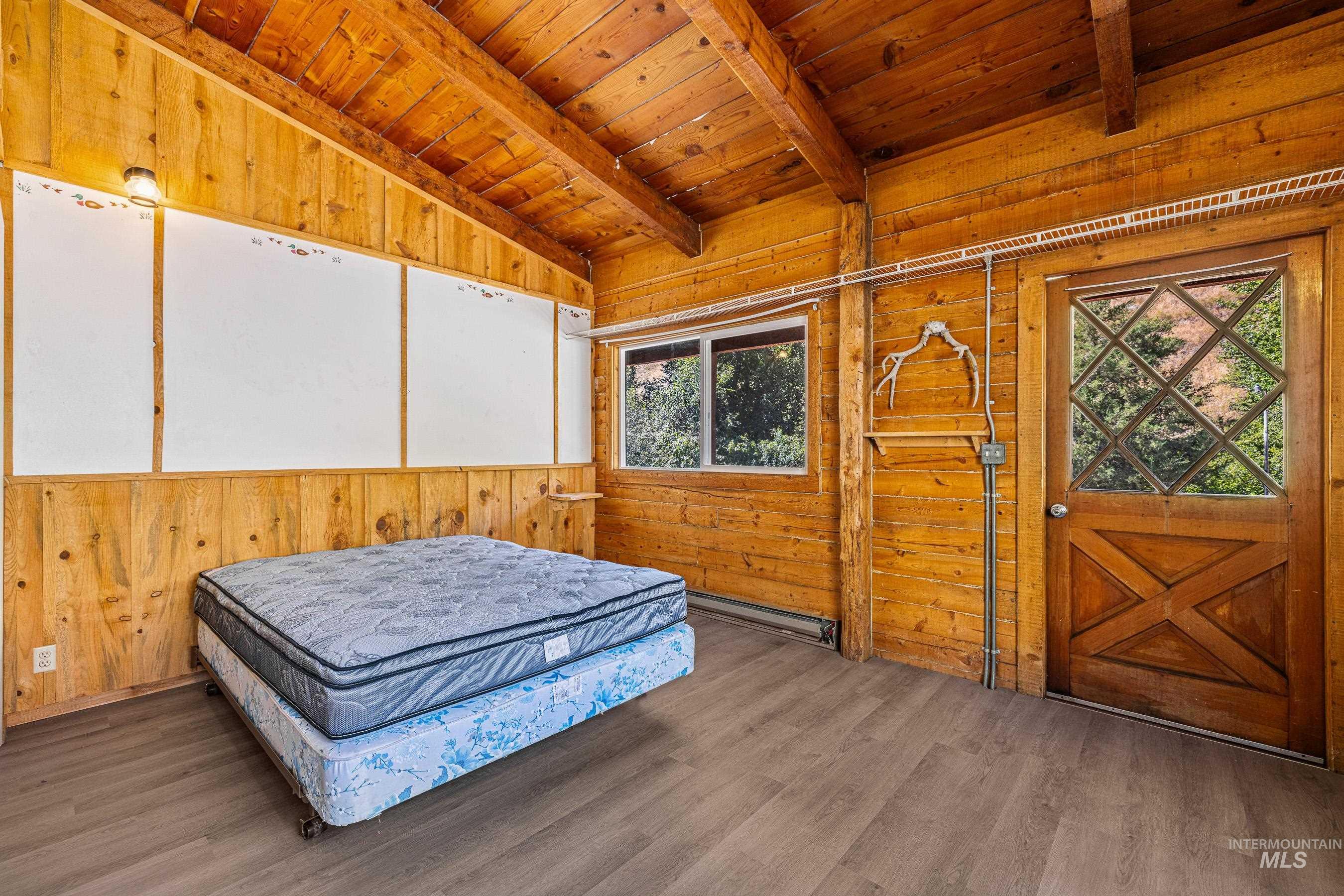 Bedroom featuring wood walls, wood ceiling, wood finished floors, and a baseboard heating unit