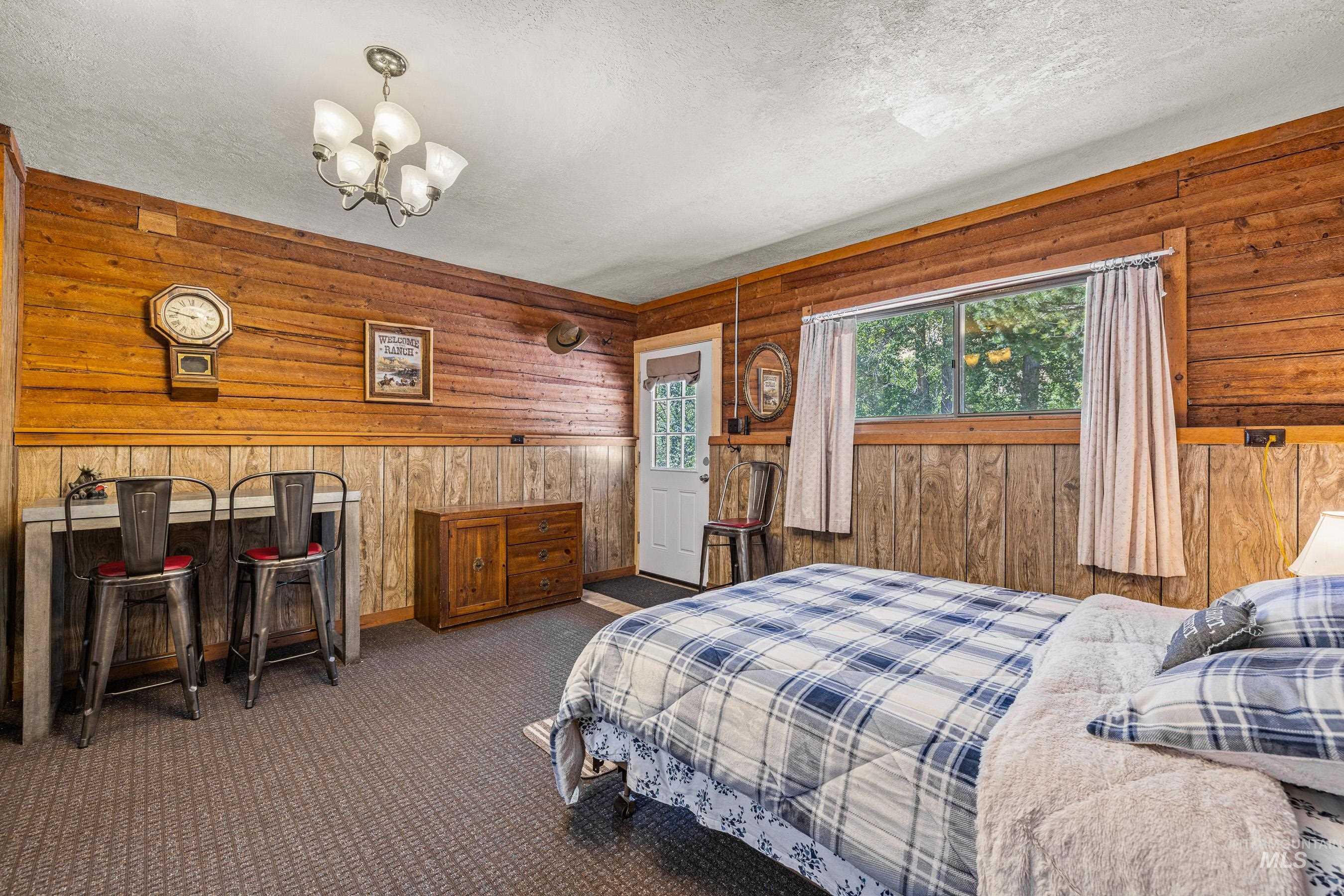 Bedroom with wood walls, a textured ceiling, carpet floors, and a chandelier