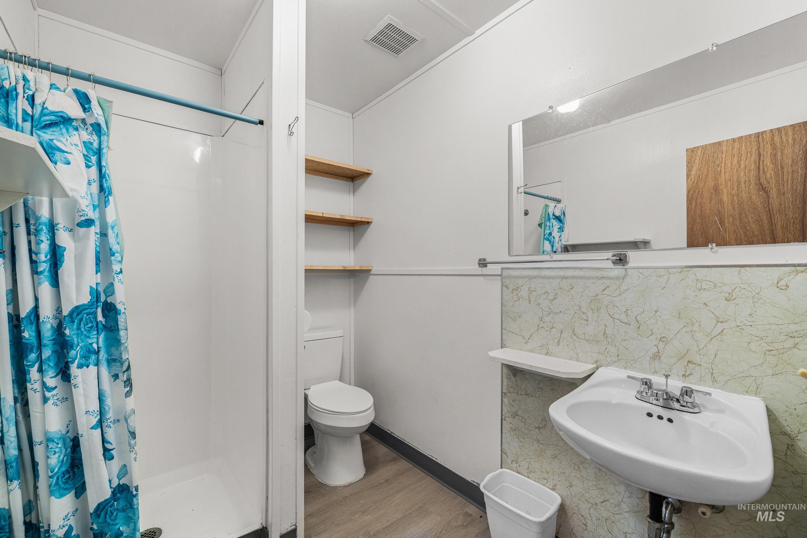 Bathroom with a stall shower, light wood-style flooring, and backsplash