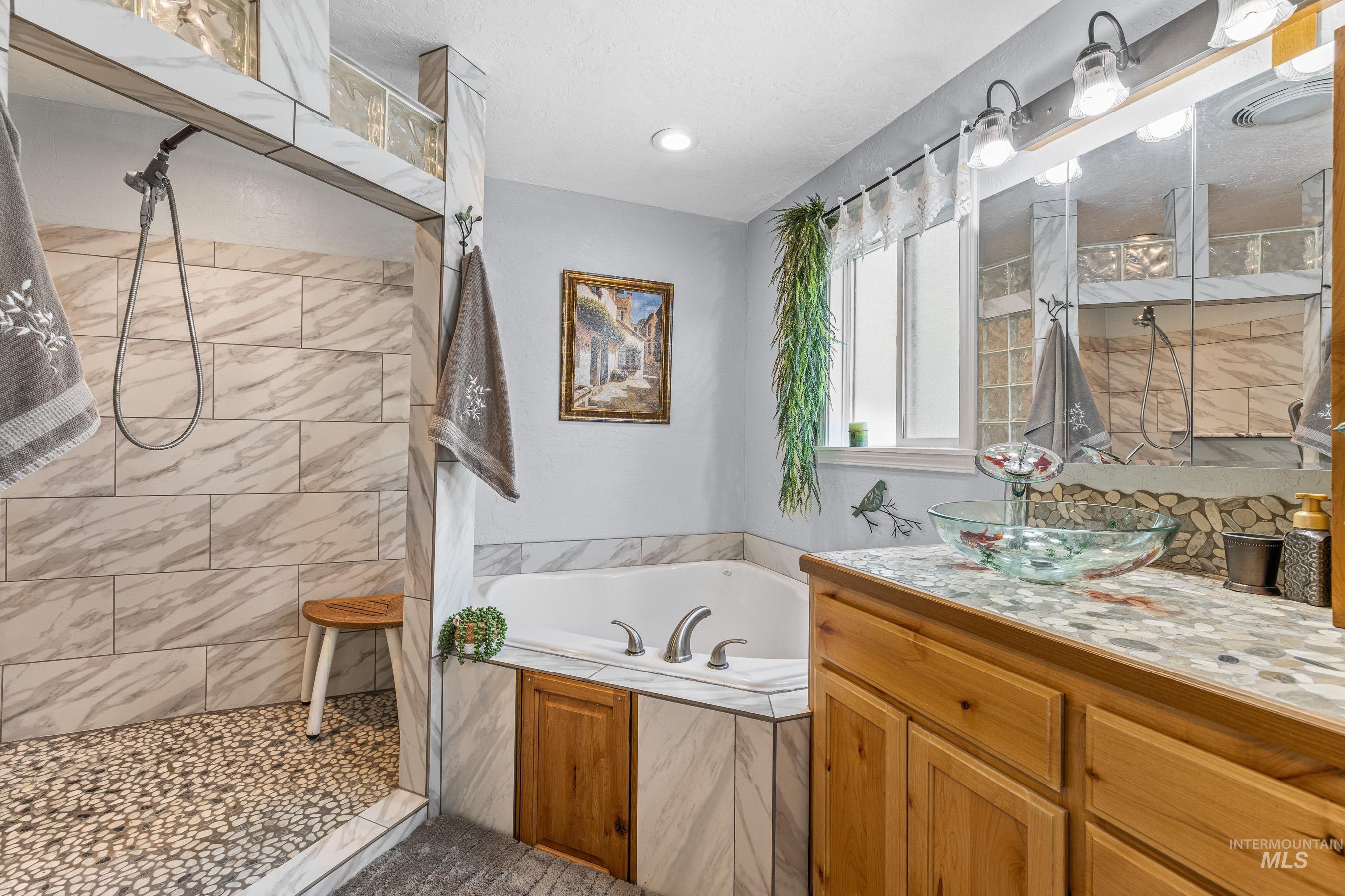 Bathroom with a tile shower, a garden tub, and vanity