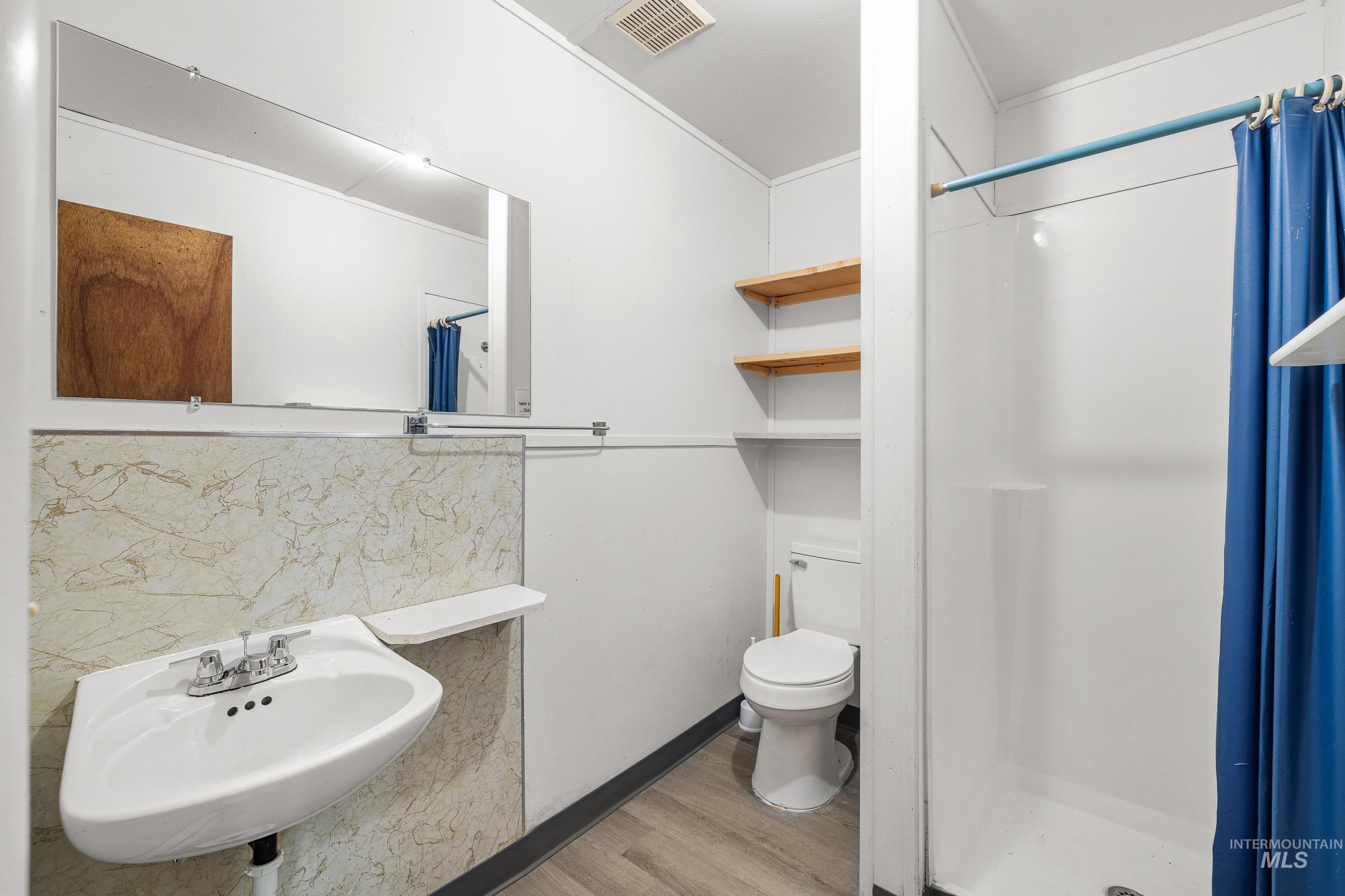 Bathroom featuring a shower stall, light wood finished floors, and decorative backsplash