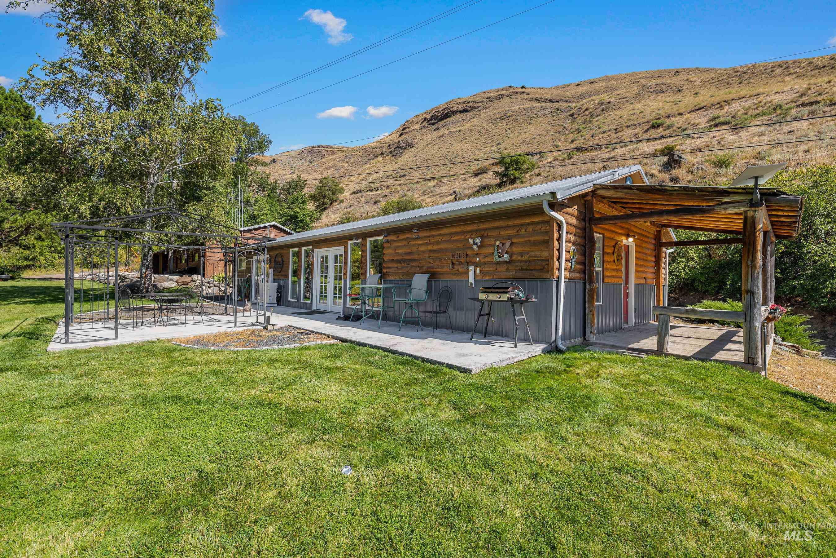 Back of property with a patio, a mountain view, a yard, and a metal roof