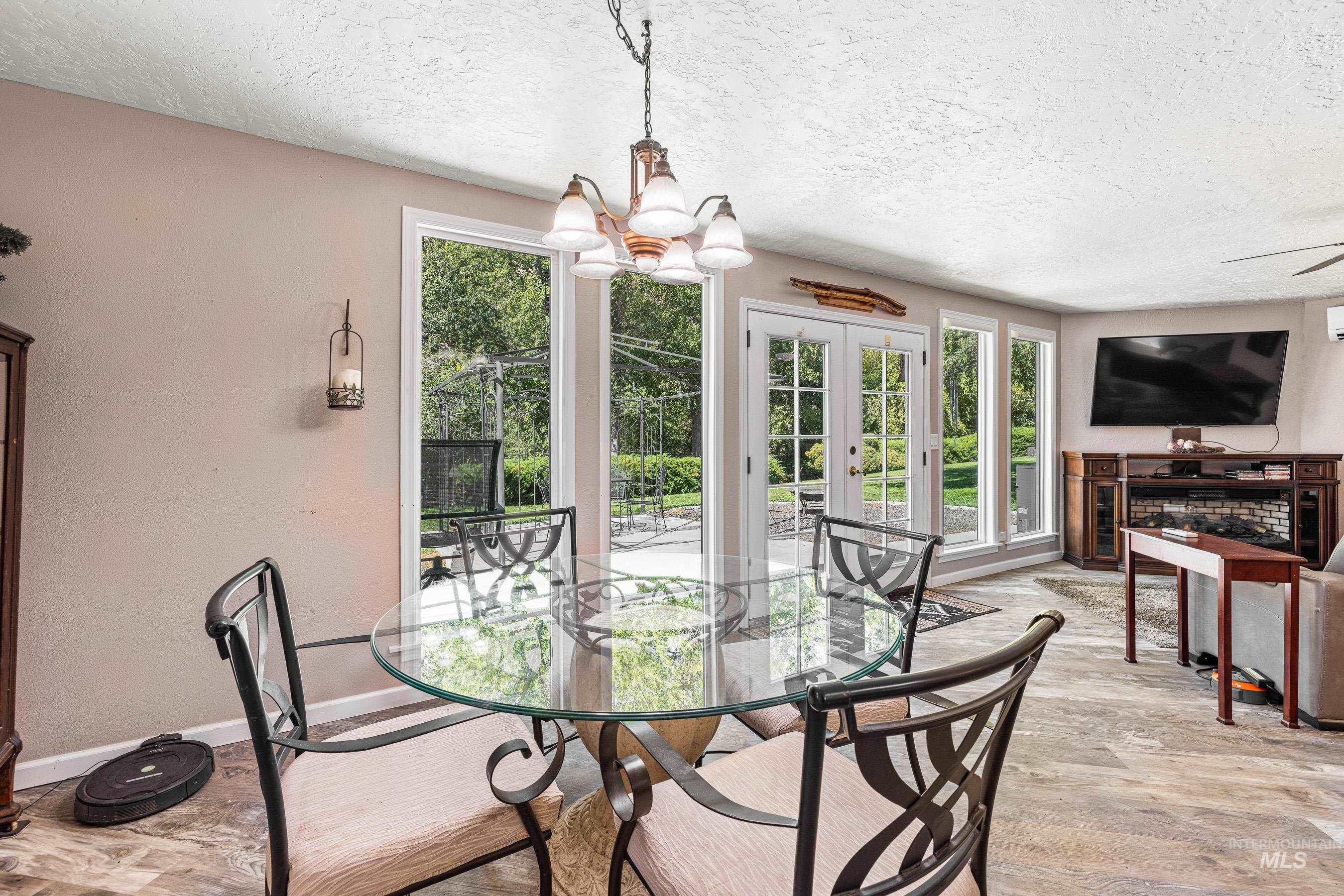 Dining room featuring light wood-type flooring, a textured ceiling, french doors, and a chandelier