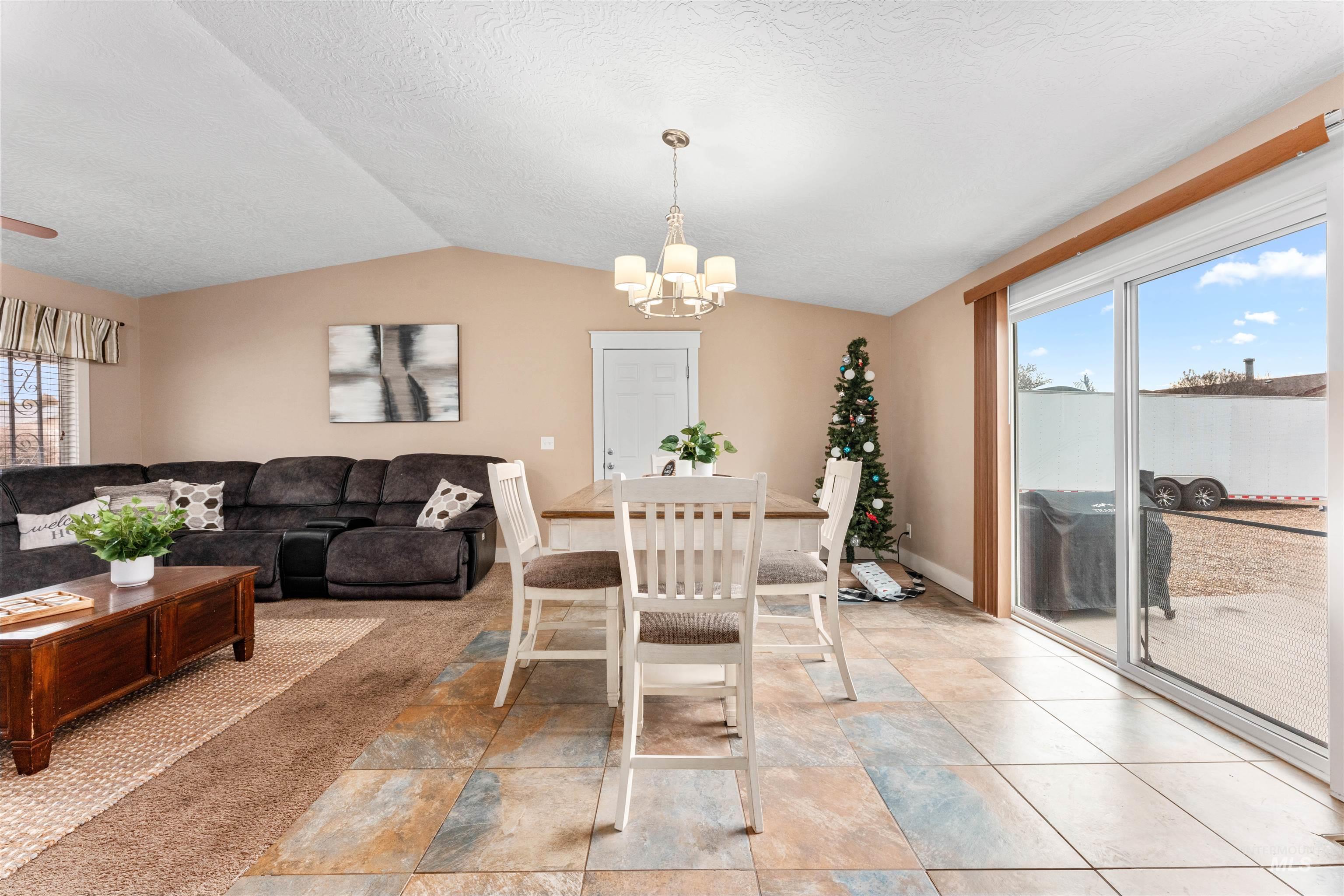 Dining room with plenty of natural light, lofted ceiling, a chandelier, and a textured ceiling