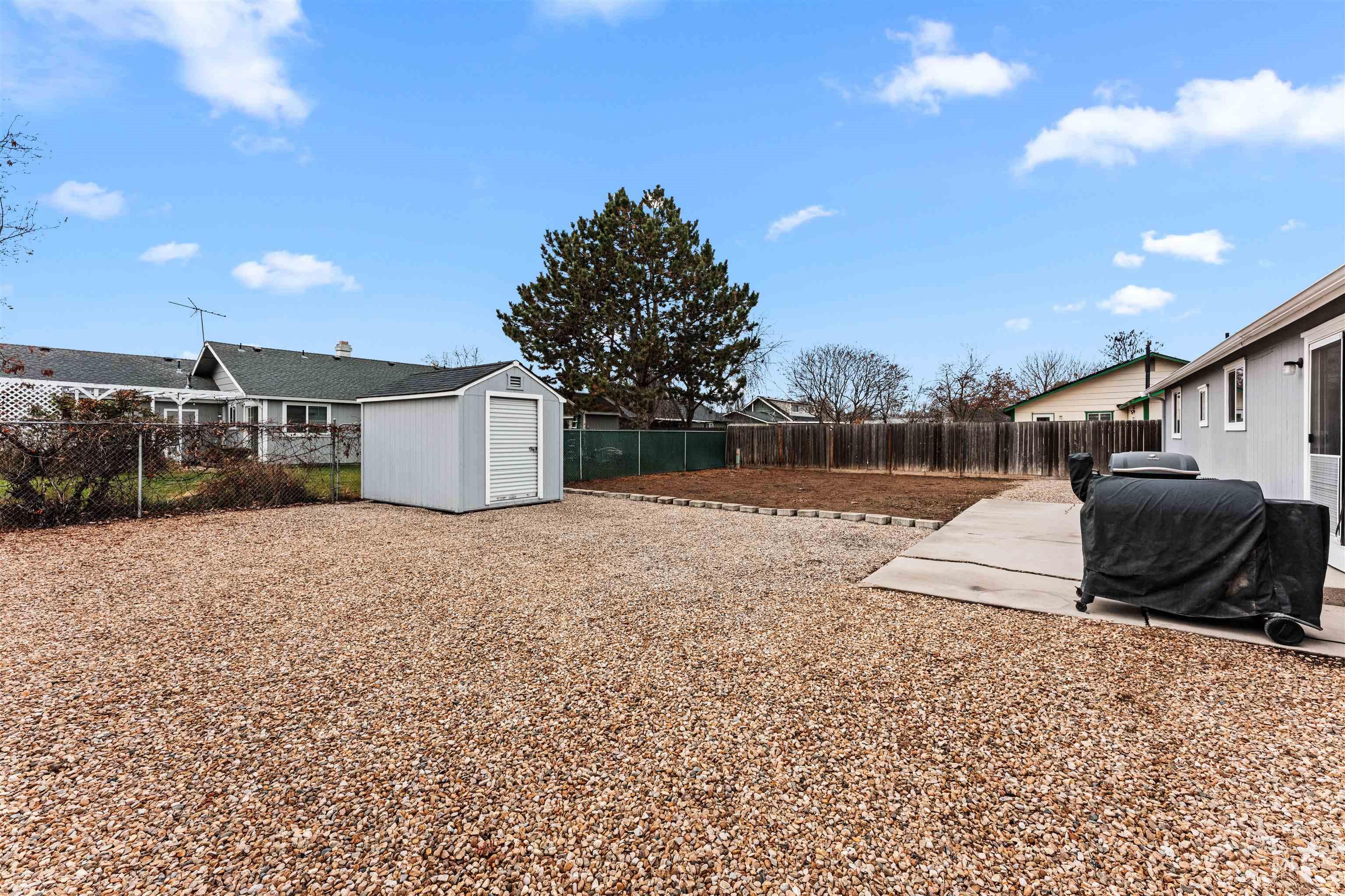 Fenced backyard featuring a storage unit and a patio