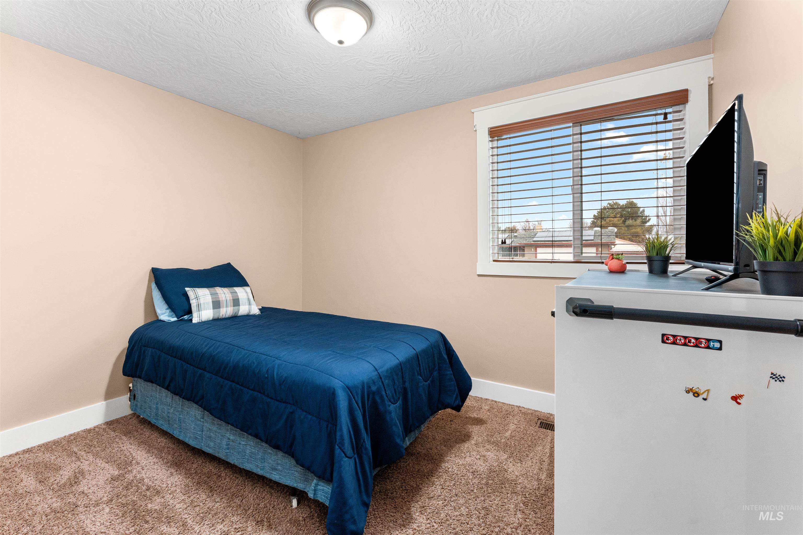 Bedroom featuring light colored carpet and a textured ceiling