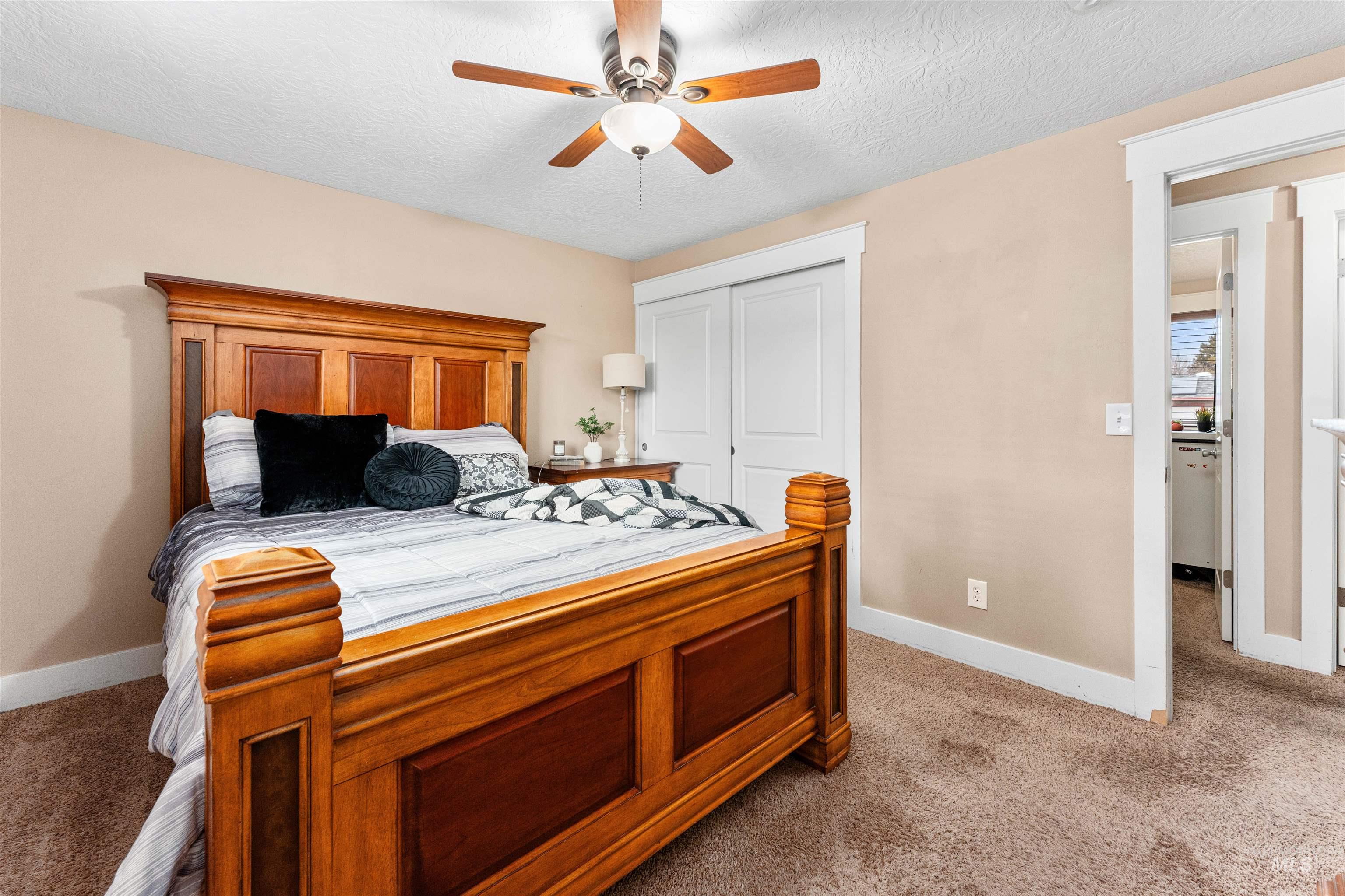 Carpeted bedroom with a ceiling fan, a closet, and a textured ceiling