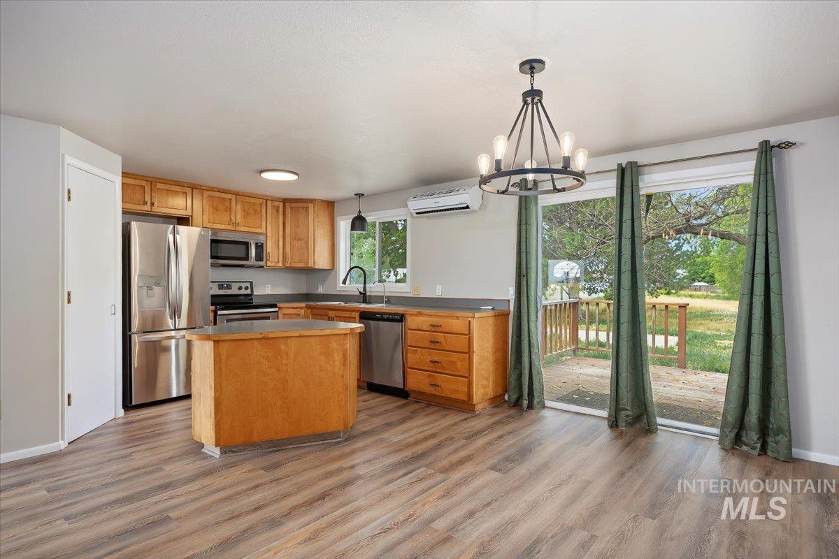 Kitchen featuring appliances with stainless steel finishes, a wall mounted AC, light wood-style flooring, and a kitchen island