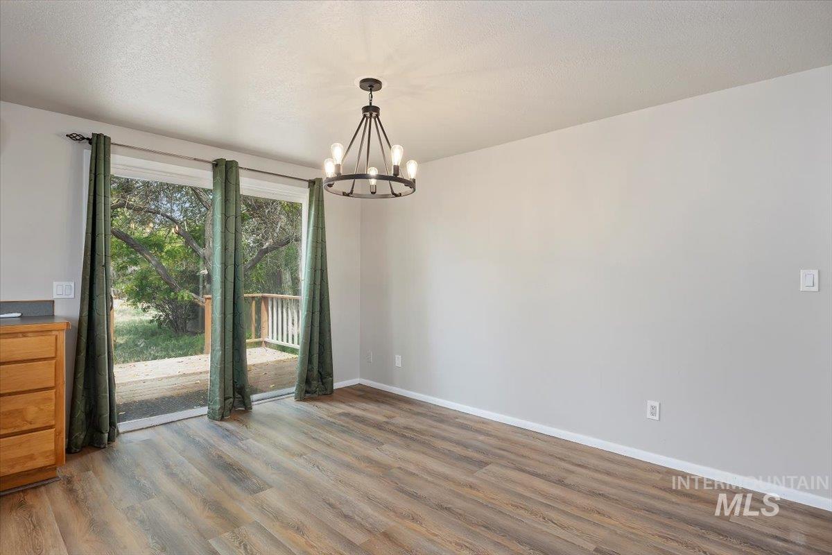 Unfurnished dining area with wood finished floors and a chandelier