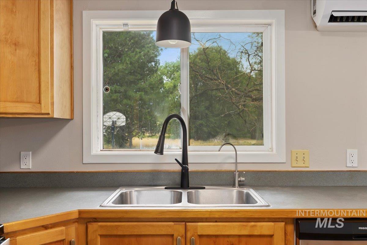 Kitchen with an AC wall unit, dishwasher, and light countertops