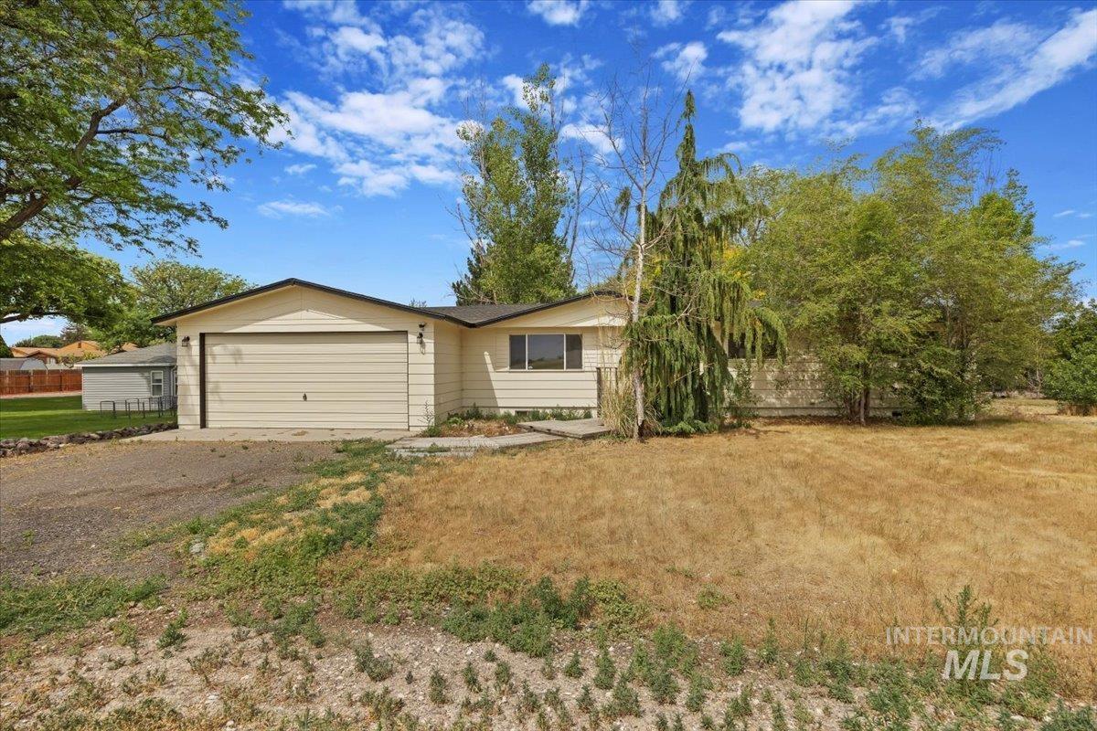 Ranch-style home with an attached garage and dirt driveway