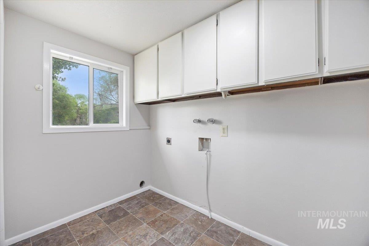 Laundry area with cabinet space, hookup for an electric dryer, washer hookup, and stone finish floors
