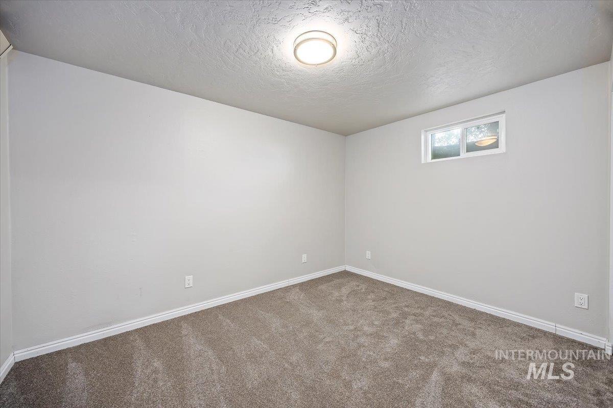 Carpeted spare room with baseboards and a textured ceiling
