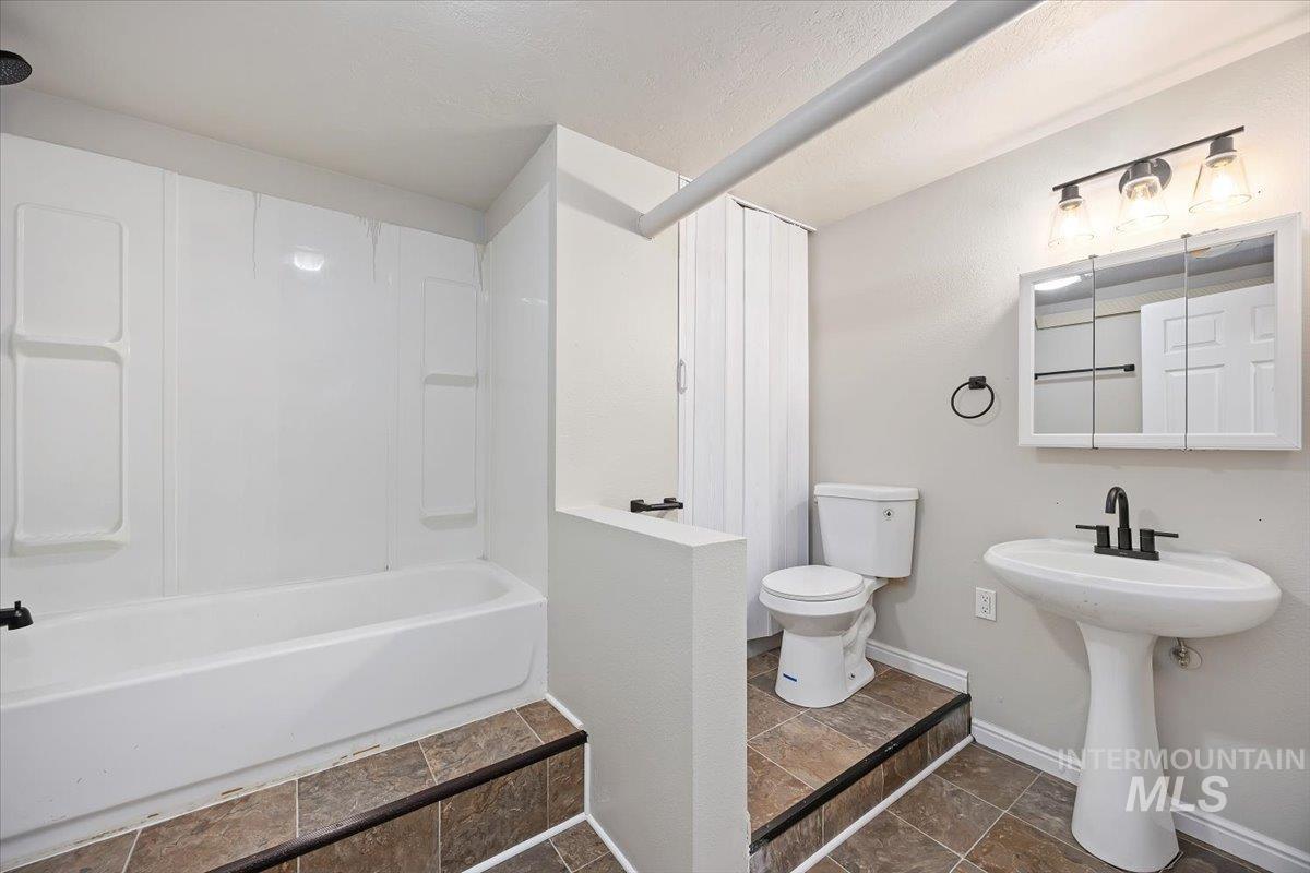 Full bathroom featuring stone tile floors and tub / shower combination