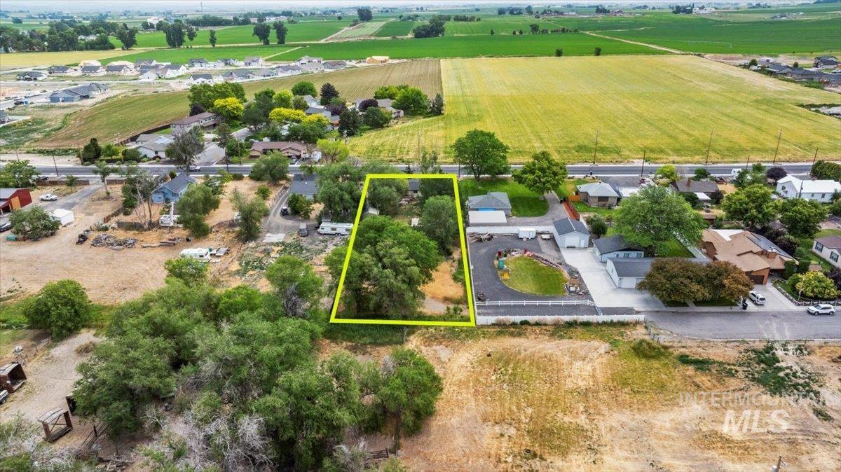 Aerial view of sparsely populated area featuring nearby suburban area, property parcel outlined, and large plots for crops