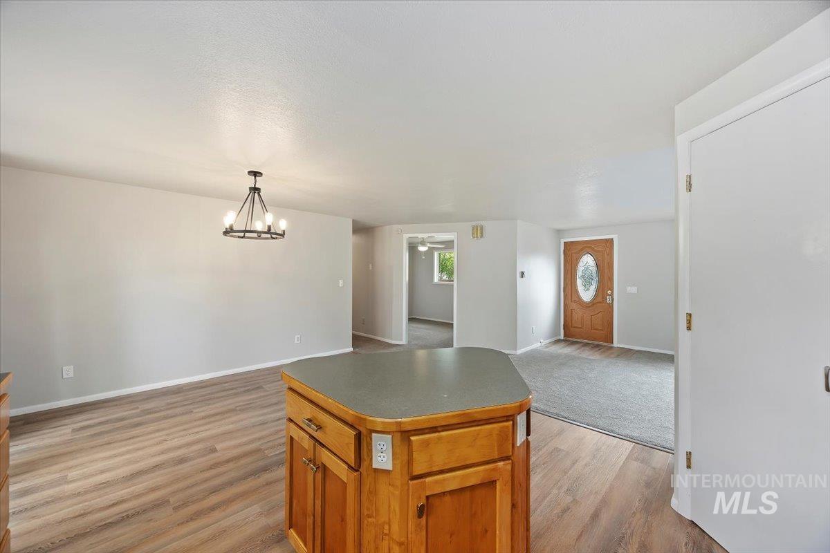 Kitchen with open floor plan, a chandelier, a center island, light wood-type flooring, and brown cabinets