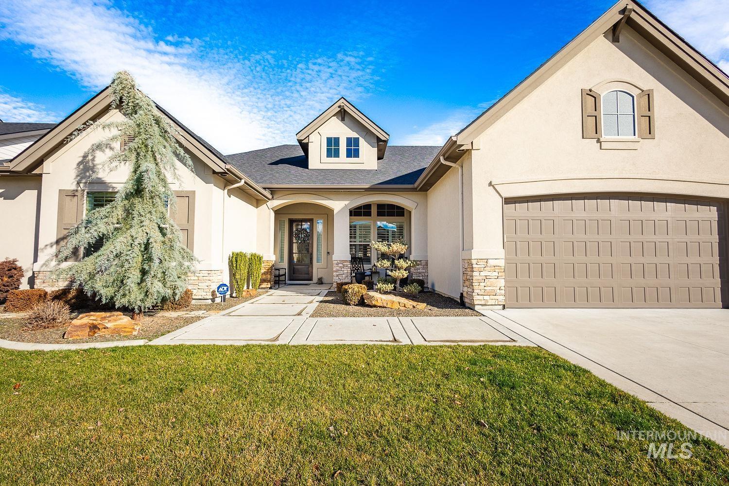 View of front of property with stone siding, stucco siding, a front yard, and a garage