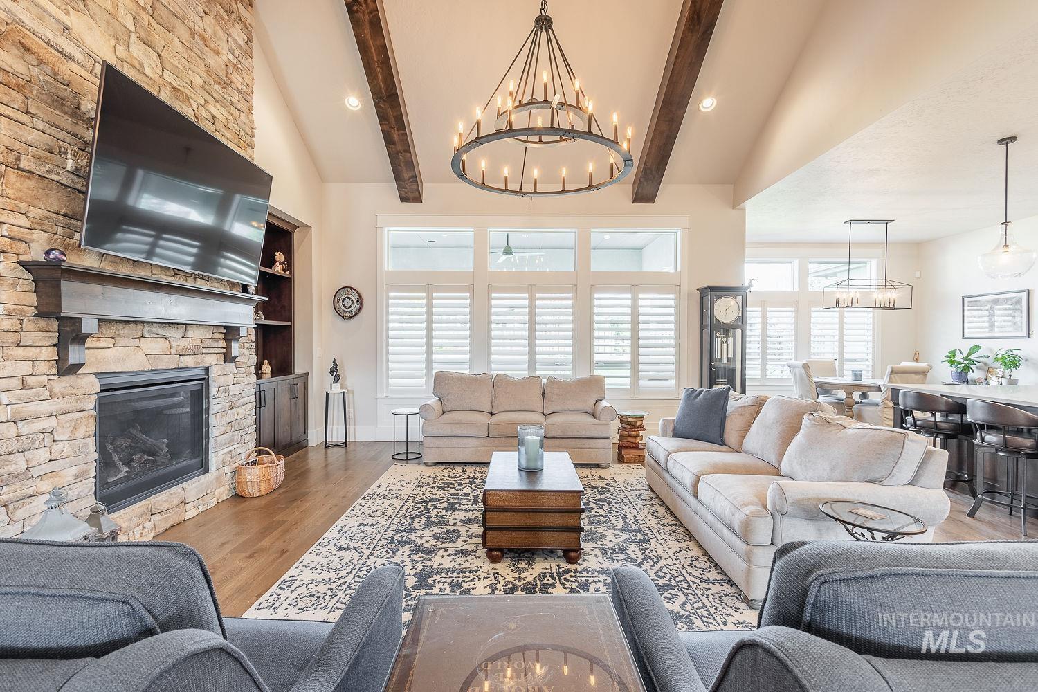Living room with wood finished floors, a stone fireplace, recessed lighting, plenty of natural light, and a chandelier