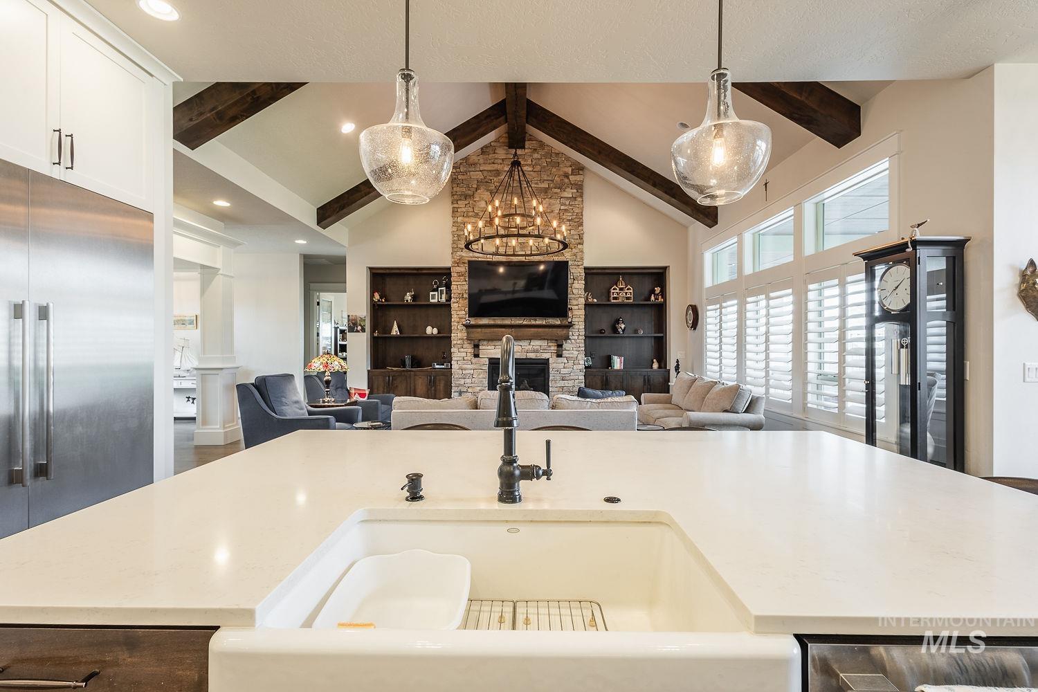 Kitchen featuring built in shelves, a stone fireplace, a center island with sink, and light stone countertops