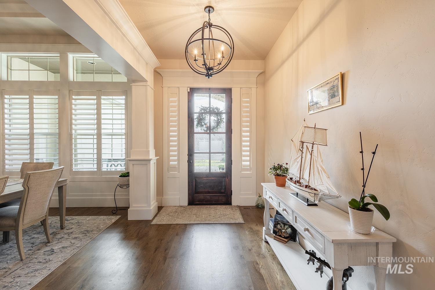 Entryway with dark wood-style flooring and a chandelier
