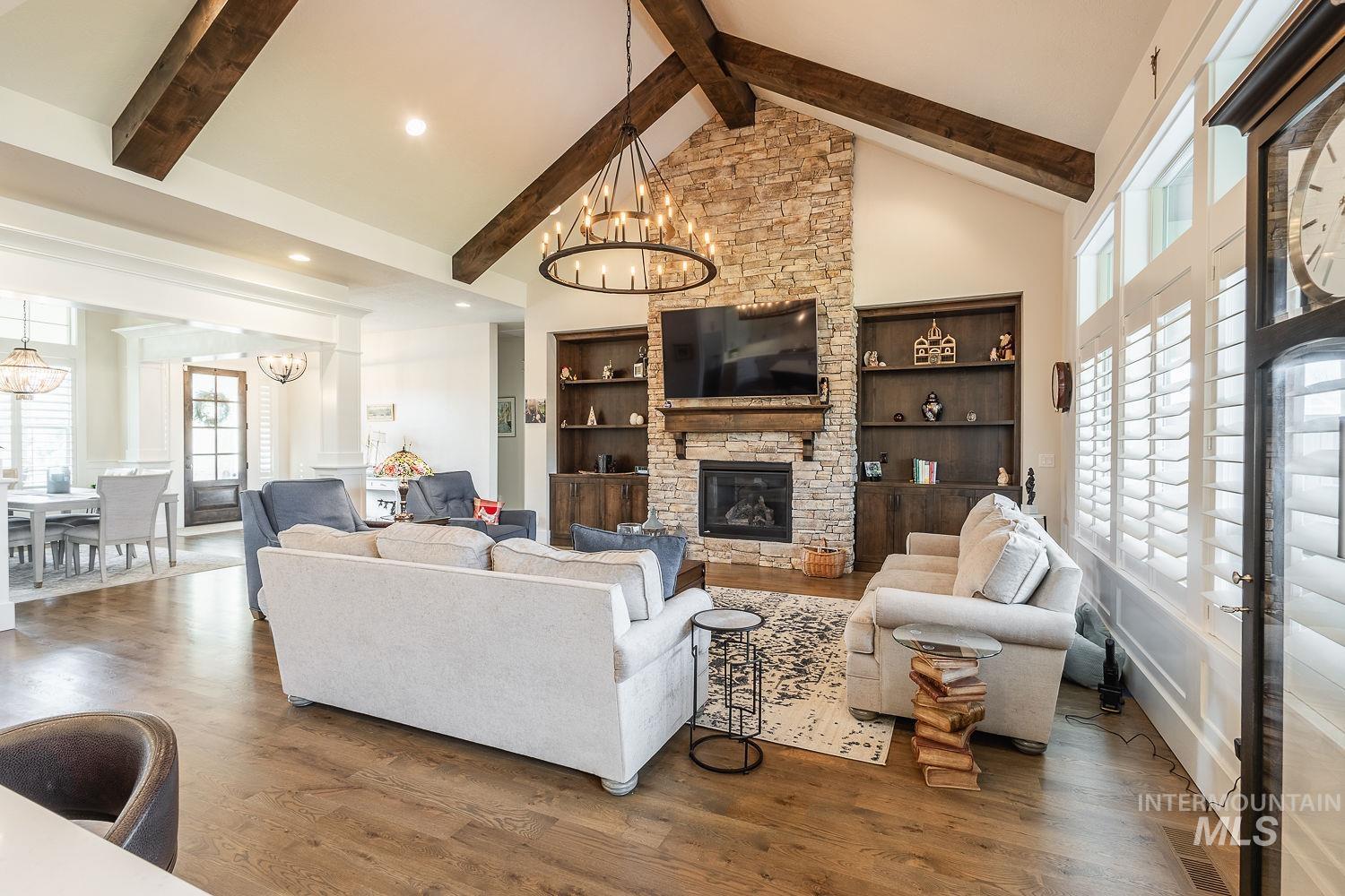 Living area featuring a fireplace, high vaulted ceiling, built in shelves, wood finished floors, and a chandelier