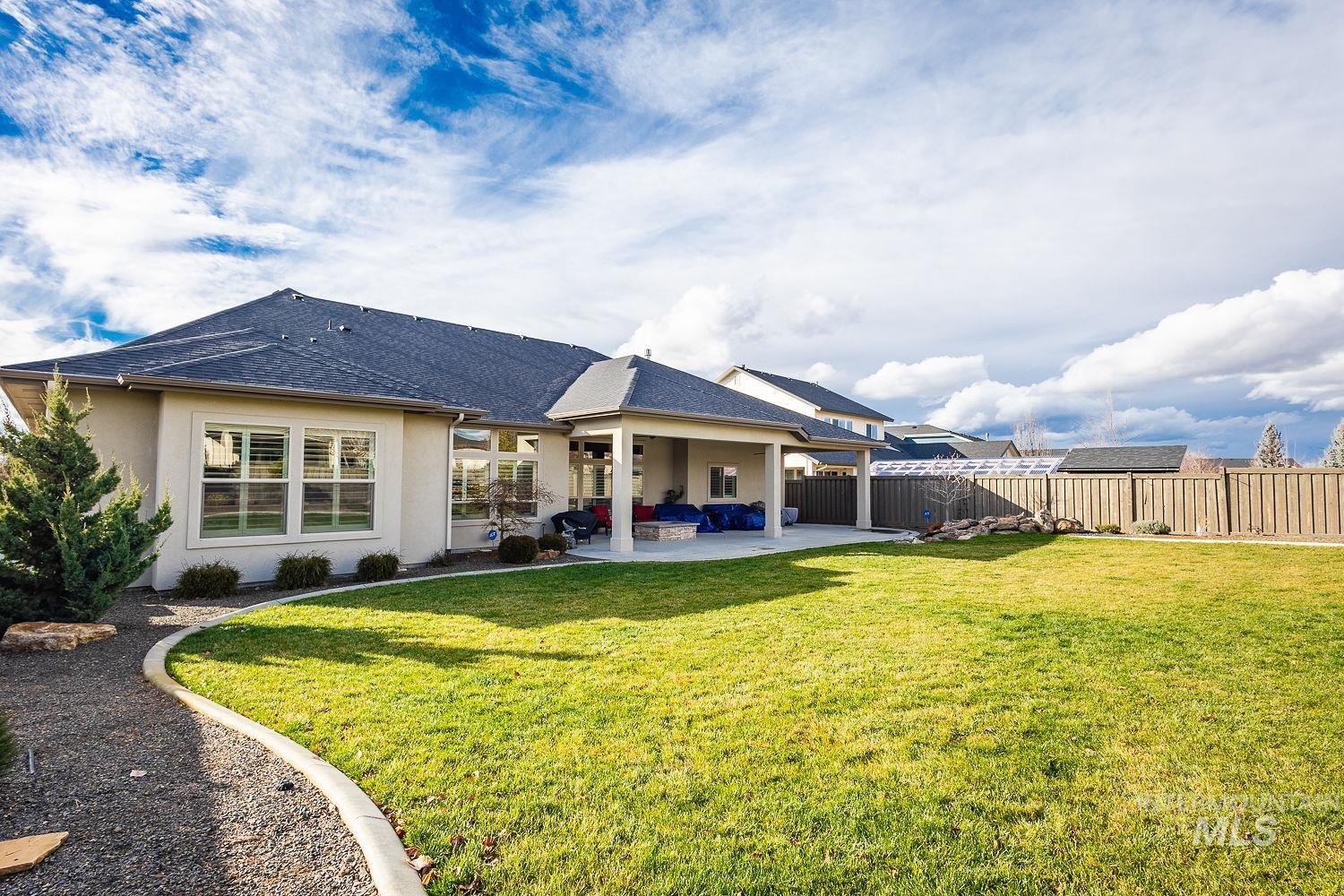 Rear view of house featuring stucco siding, a patio area, a fenced backyard, and roof with shingles