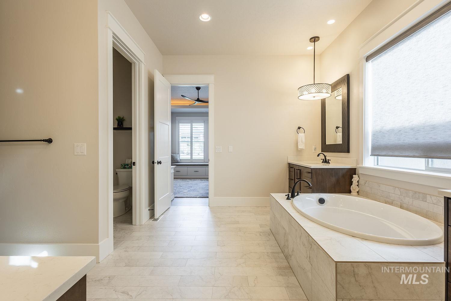 Full bath with vanity, a bath, recessed lighting, ceiling fan, and light marble finish floors