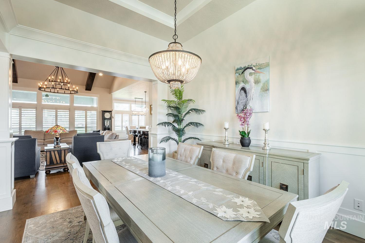Dining room featuring dark wood-style floors, a chandelier, a wainscoted wall, and a decorative wall