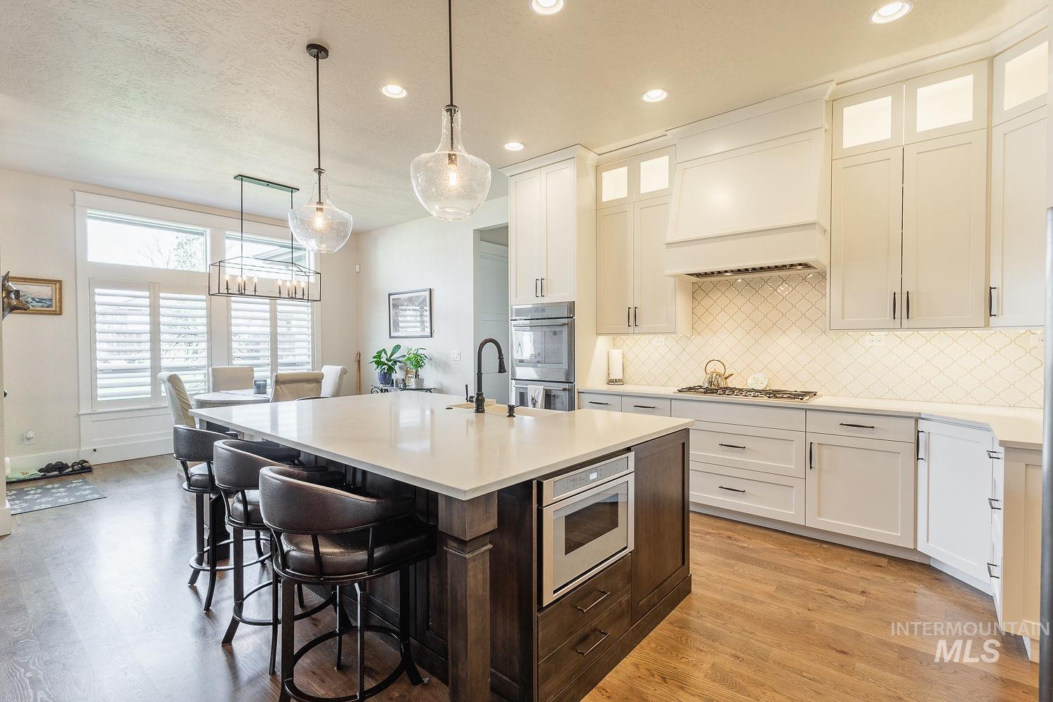 Kitchen with dark brown cabinetry, a breakfast bar area, an island with sink, hanging light fixtures, and light wood-style floors