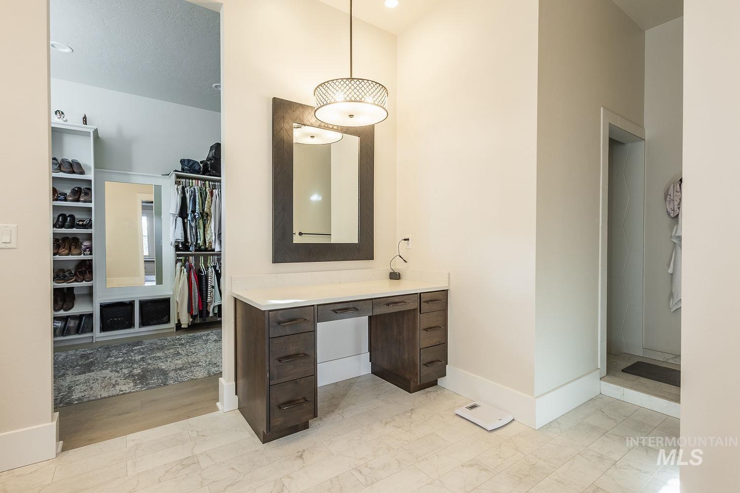 Bathroom with a spacious closet, vanity, and light marble finish flooring
