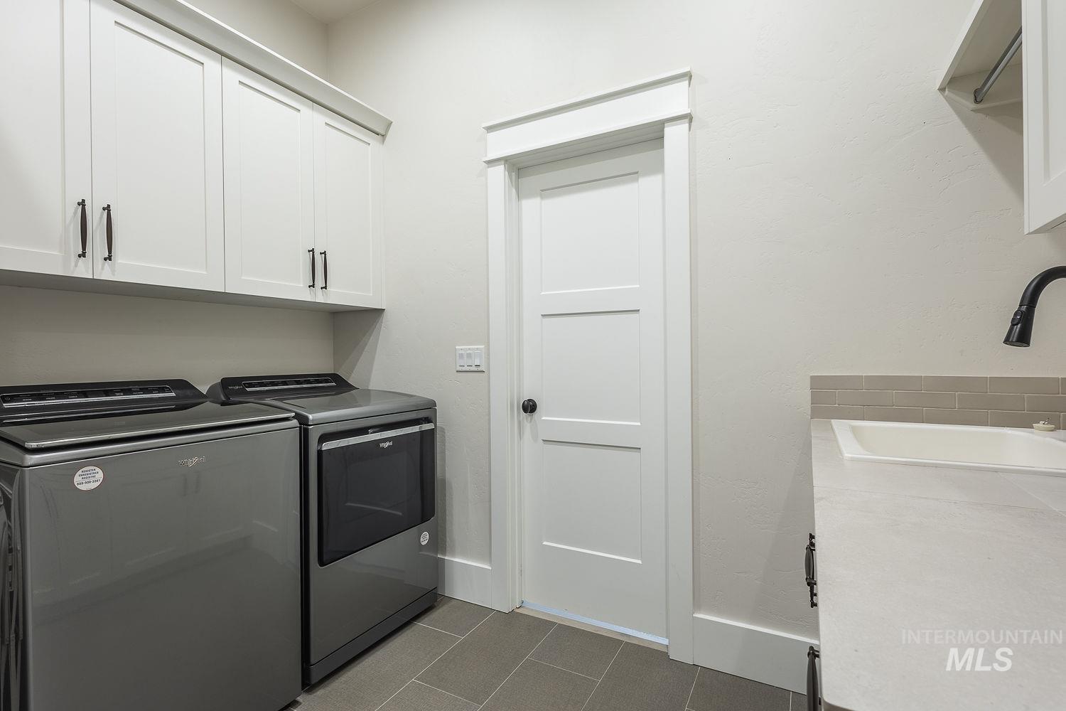 Washroom with washing machine and dryer, cabinet space, and dark tile patterned flooring