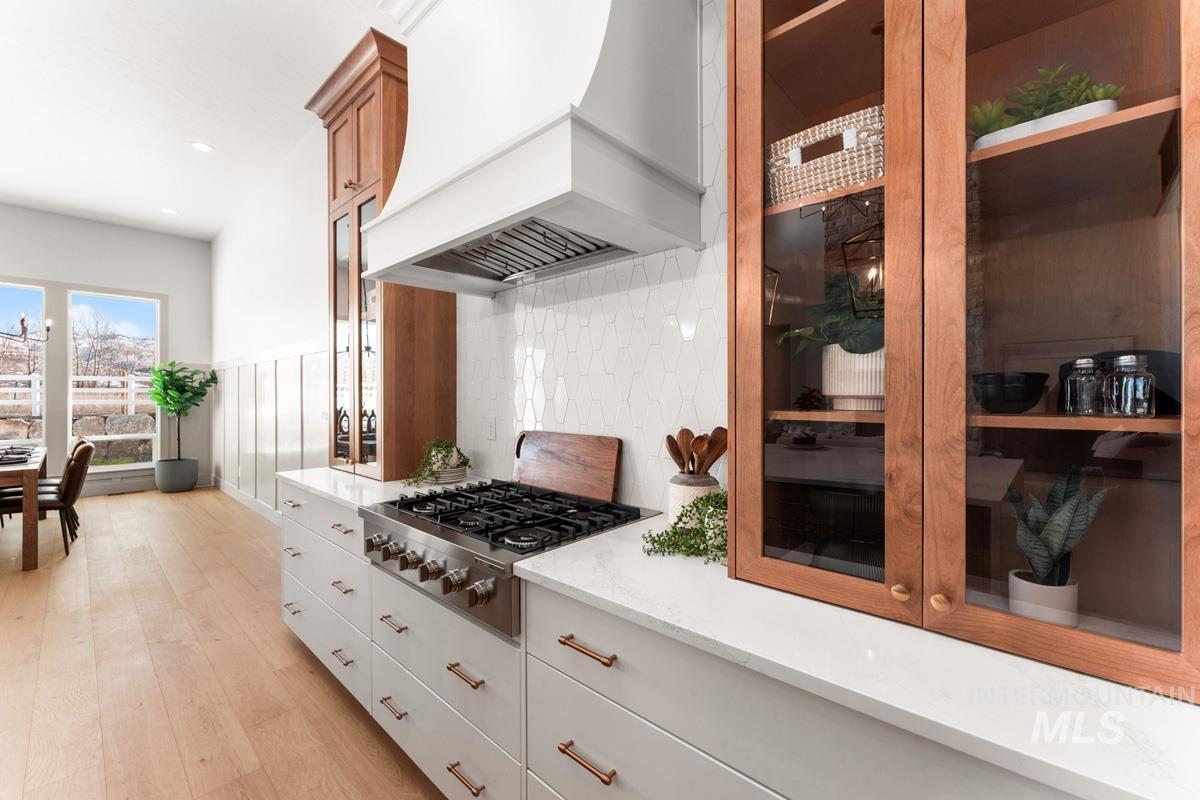 Kitchen with stainless steel gas cooktop, light stone countertops, light wood-style floors, recessed lighting, and backsplash