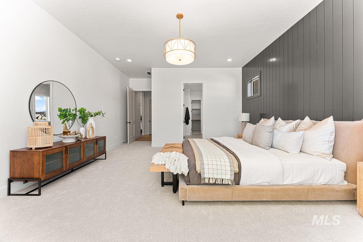 Bedroom with wood walls, a spacious closet, light colored carpet, and an accent wall