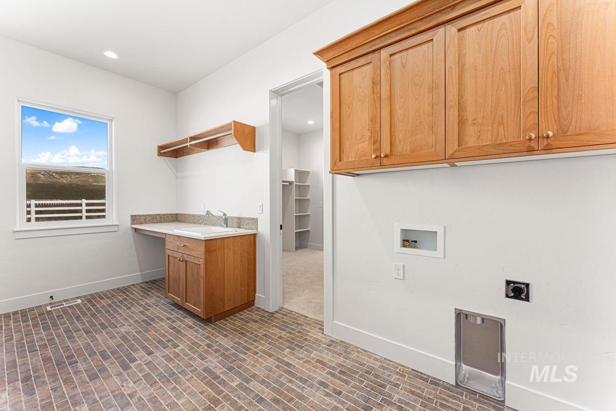 Laundry area featuring brick patterned flooring, cabinet space, hookup for a washing machine, hookup for an electric dryer, and recessed lighting