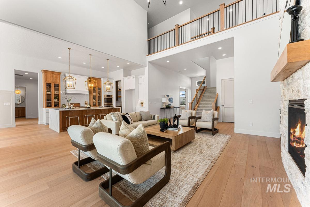 Living room featuring a stone fireplace, light wood-type flooring, and a chandelier