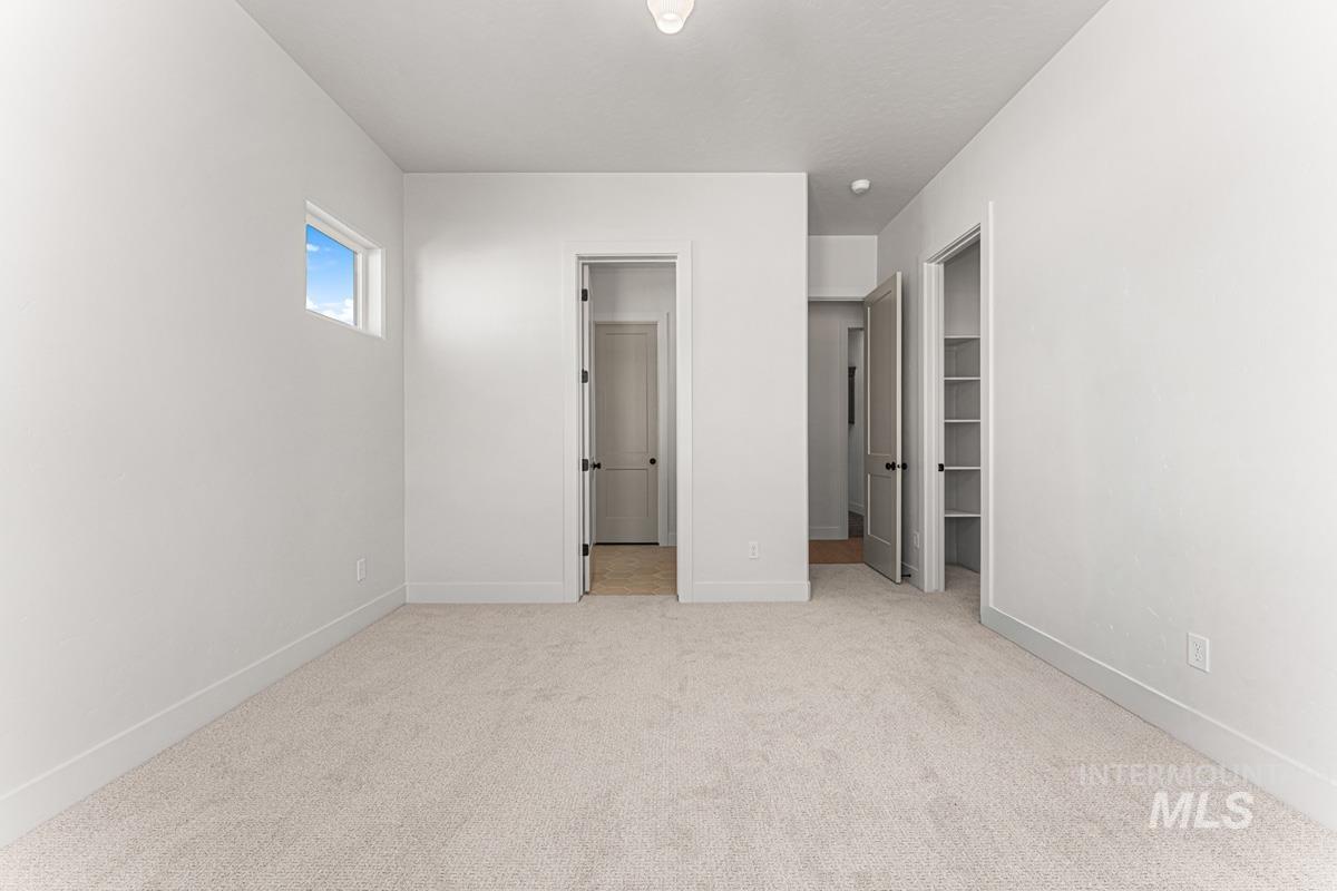 Unfurnished bedroom with a walk in closet and light carpet