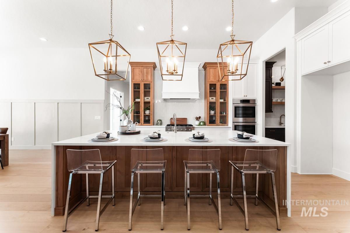Dual tone kitchen with a kitchen breakfast bar, a large island, glass fronted cabinets, light wood-style flooring, and dual tone cabinets